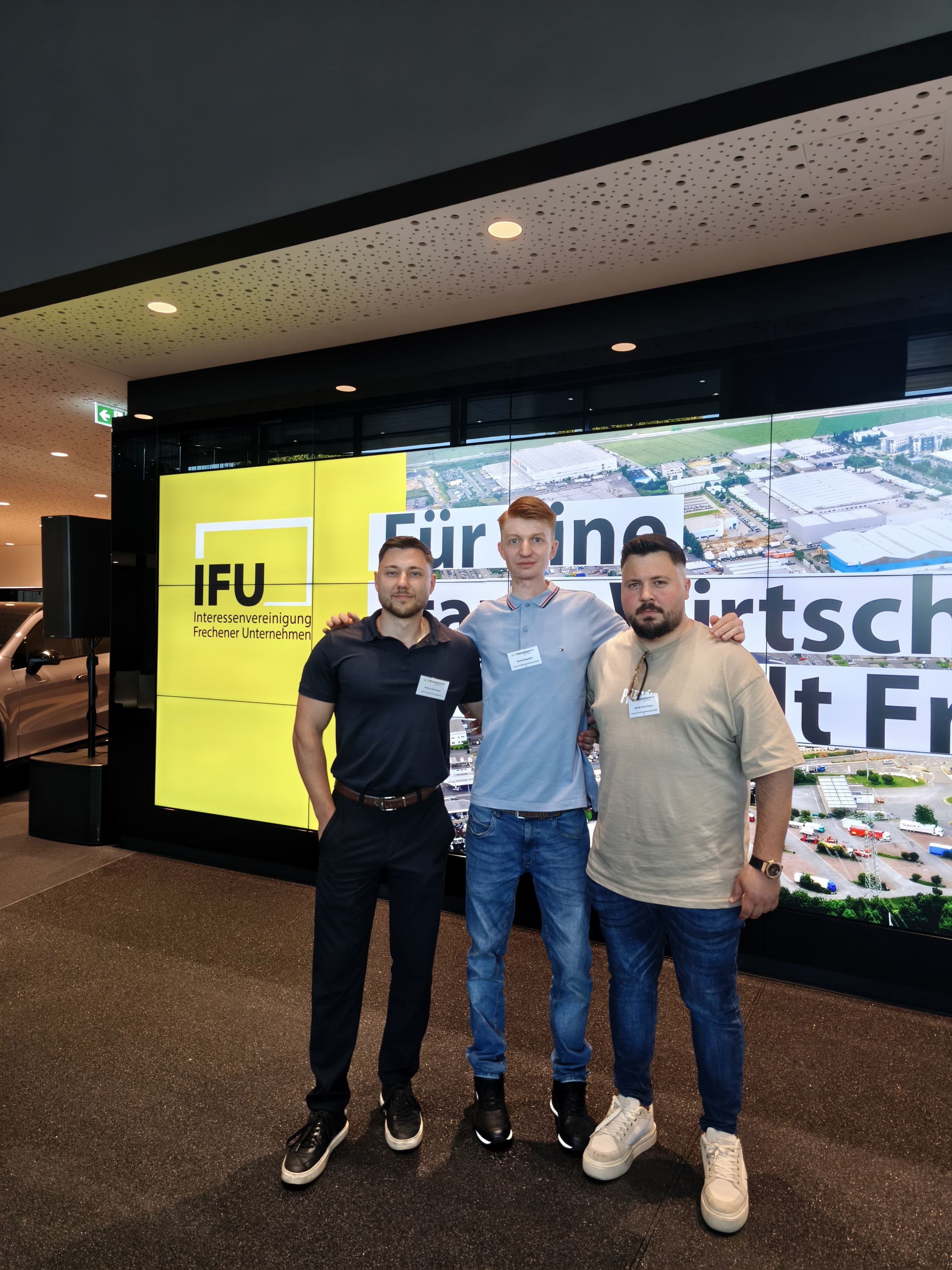Auf dem Bild sind drei junge Männer in Poloshirts zu sehen.