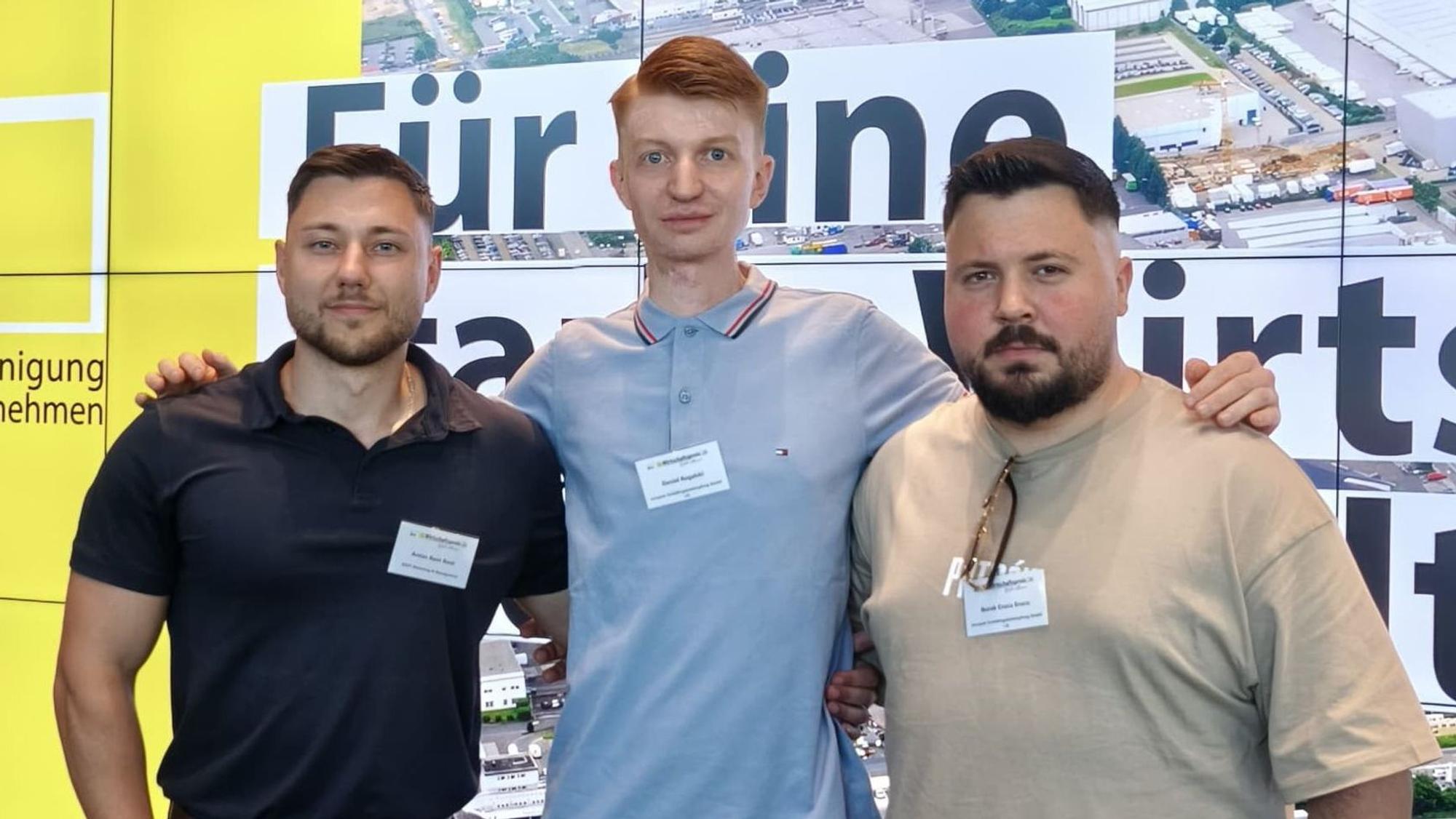 Auf dem Bild sind drei junge Männer in Poloshirts zu sehen.