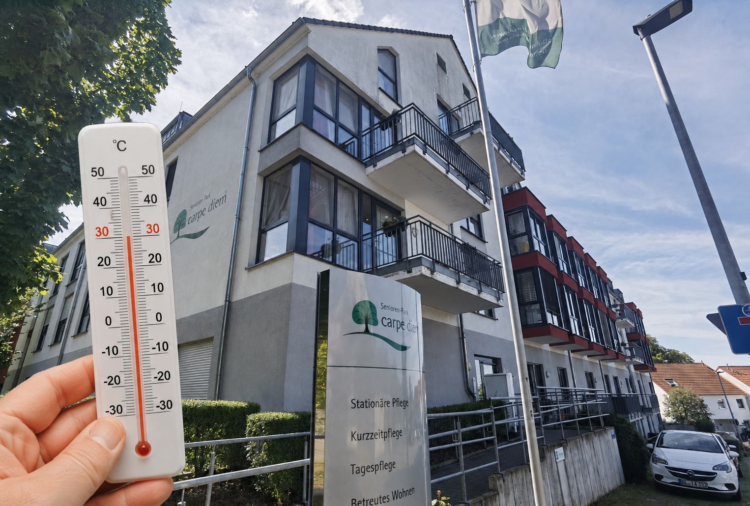 Zu sehen ist ein Bild von einem Seniorenwohnheim mit einem Thermometer davor.