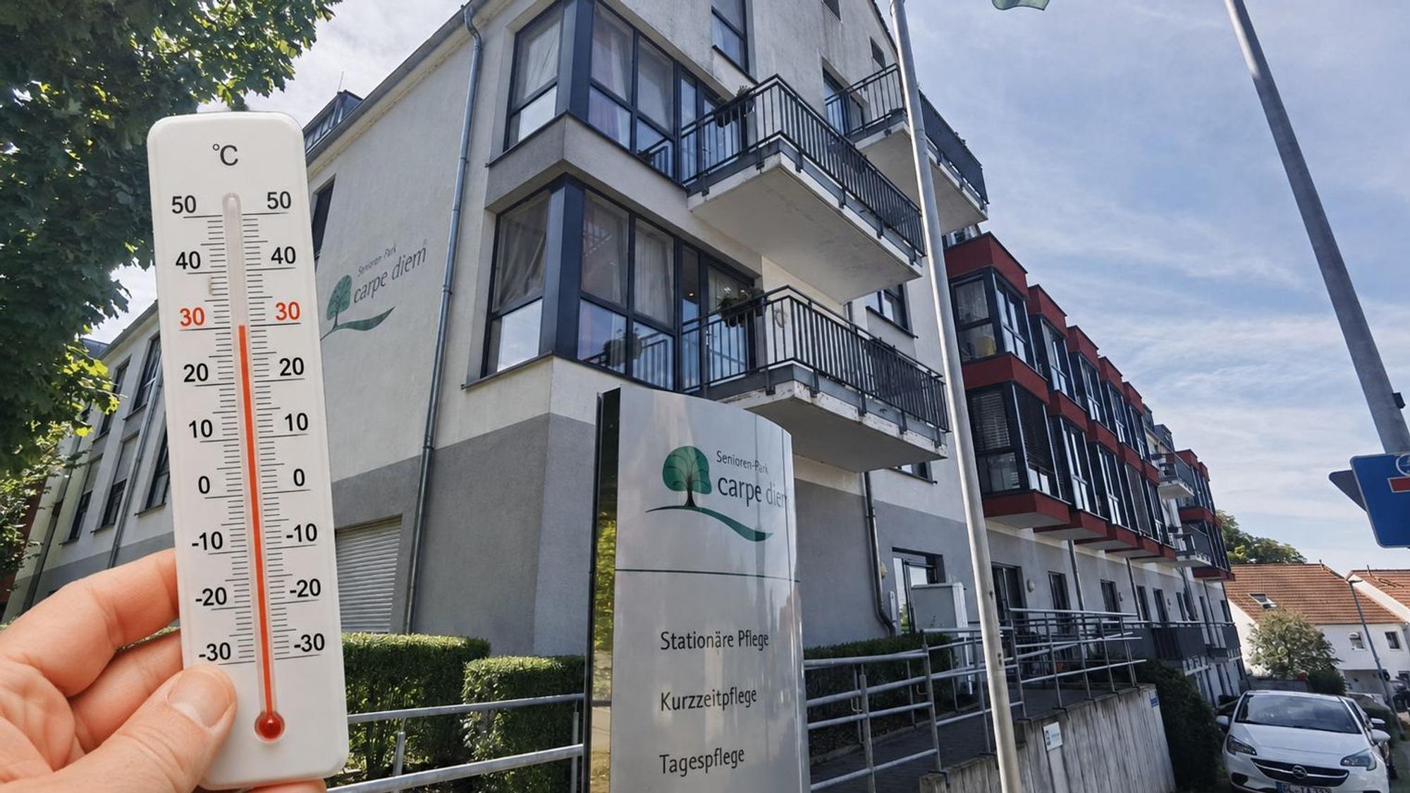 Zu sehen ist ein Bild von einem Seniorenwohnheim mit einem Thermometer davor.