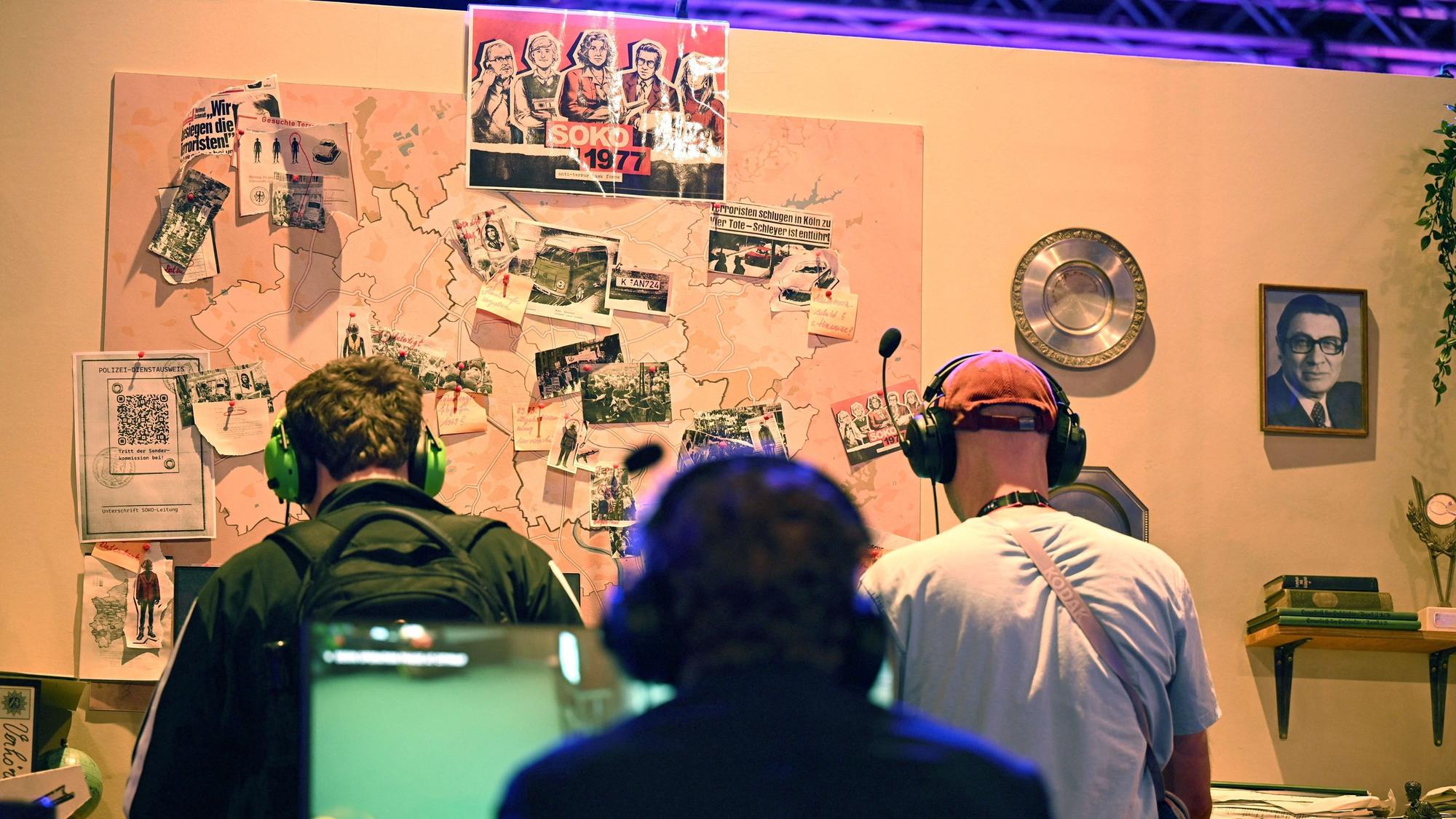 Besucher der Gamescom sitzen am Messestand der Bundeszentrale für politische Bildung und spielen das Serious Game „Soko 1977“, das den RAF-Terror der 1970er Jahre thematisiert und vom Berliner Studio Paintbucket Game entwickelt wurde.