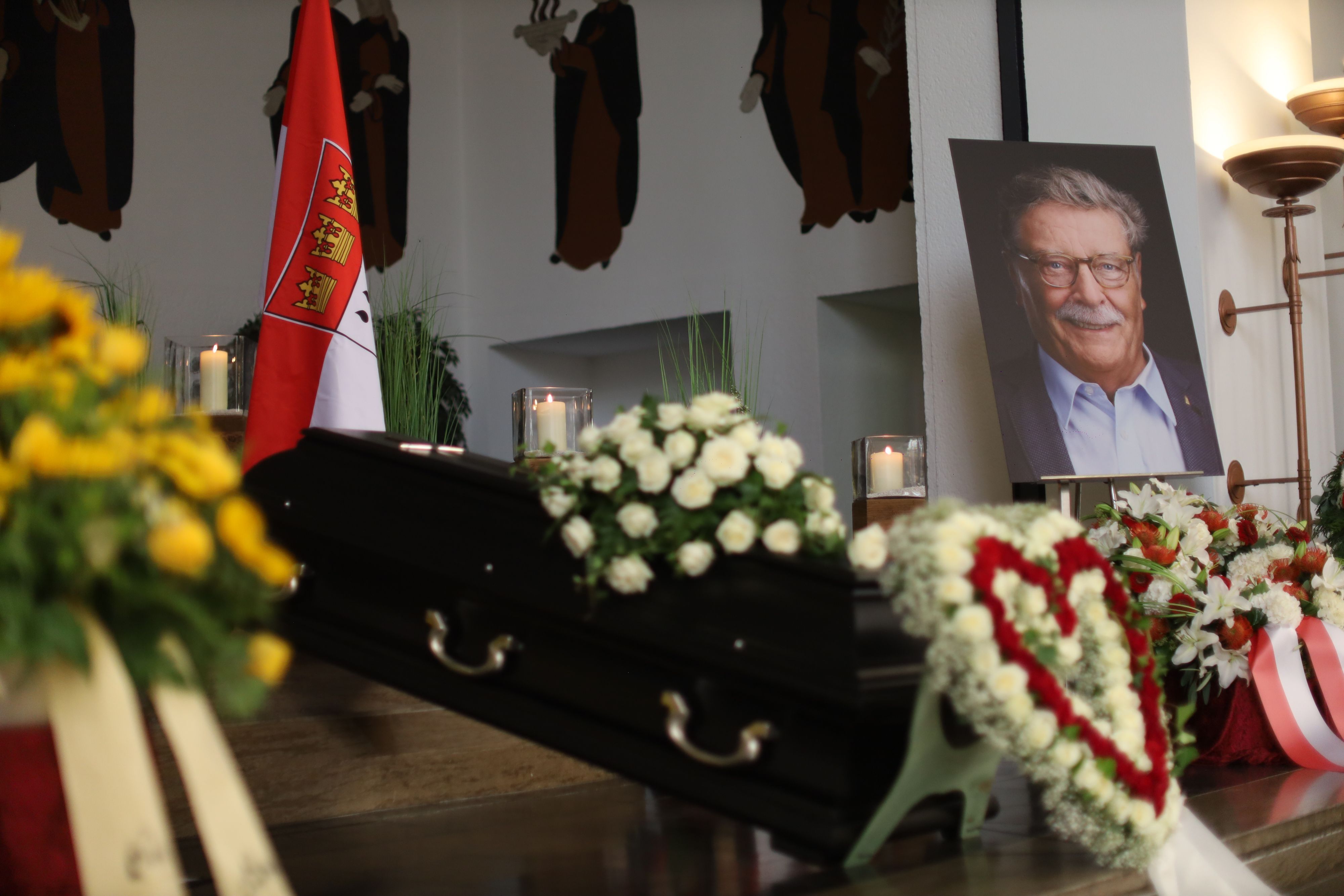 Ein Herz aus Blumen und zahlreiche Kränze umgeben den Sarg von Fritz Schramma.