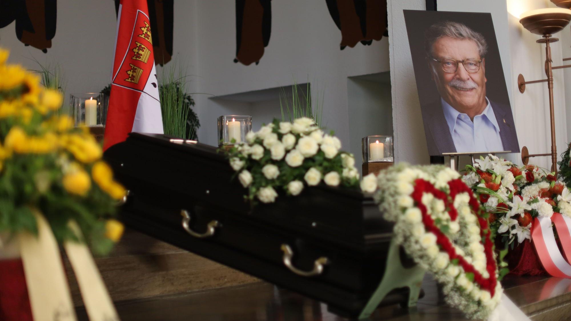 Ein Herz aus Blumen und zahlreiche Kränze umgeben den Sarg von Fritz Schramma.