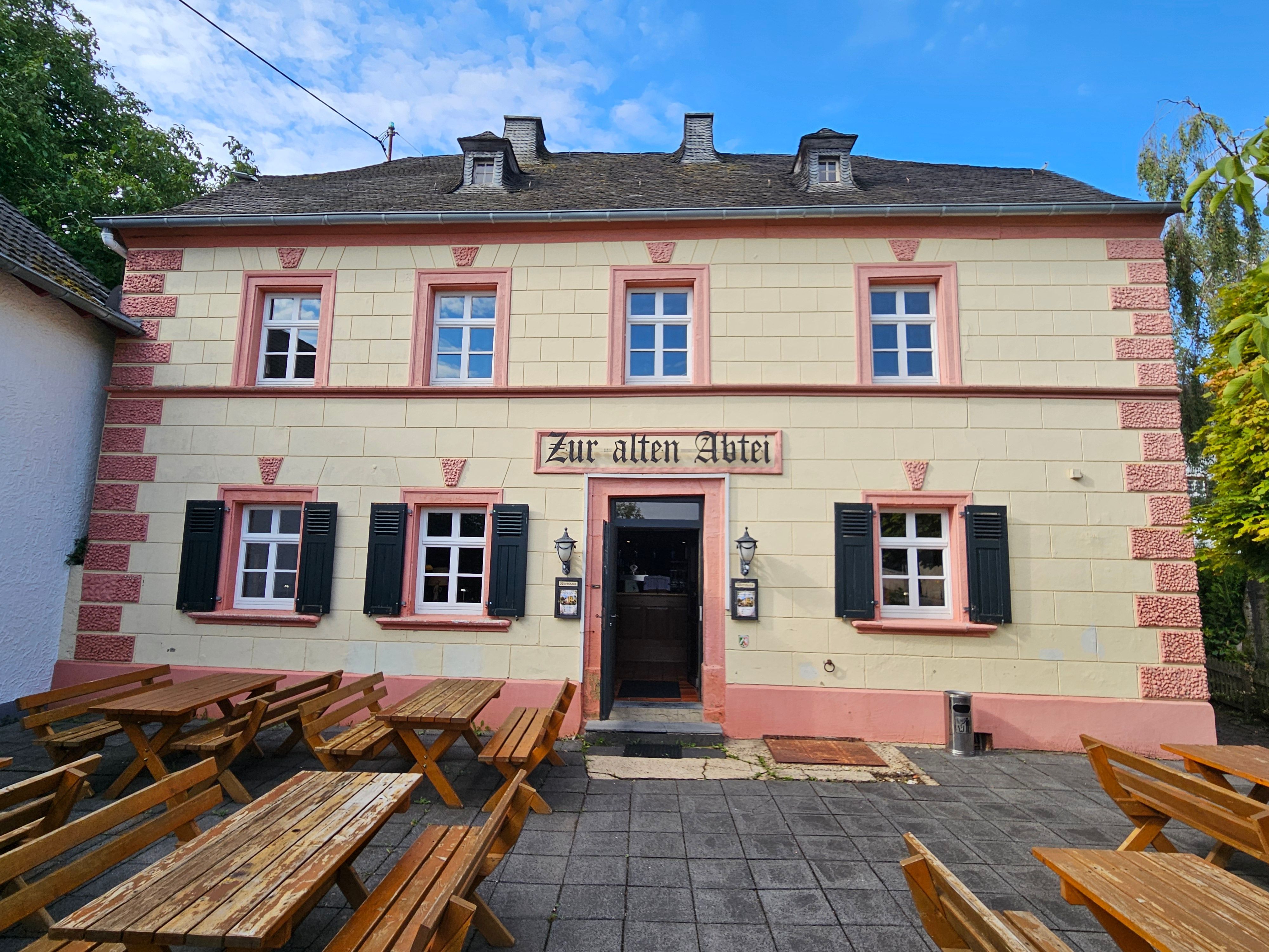 Blick auf die Fassade des Hauses mit dem Schild „Zur alten Abtei“ über der Tür.