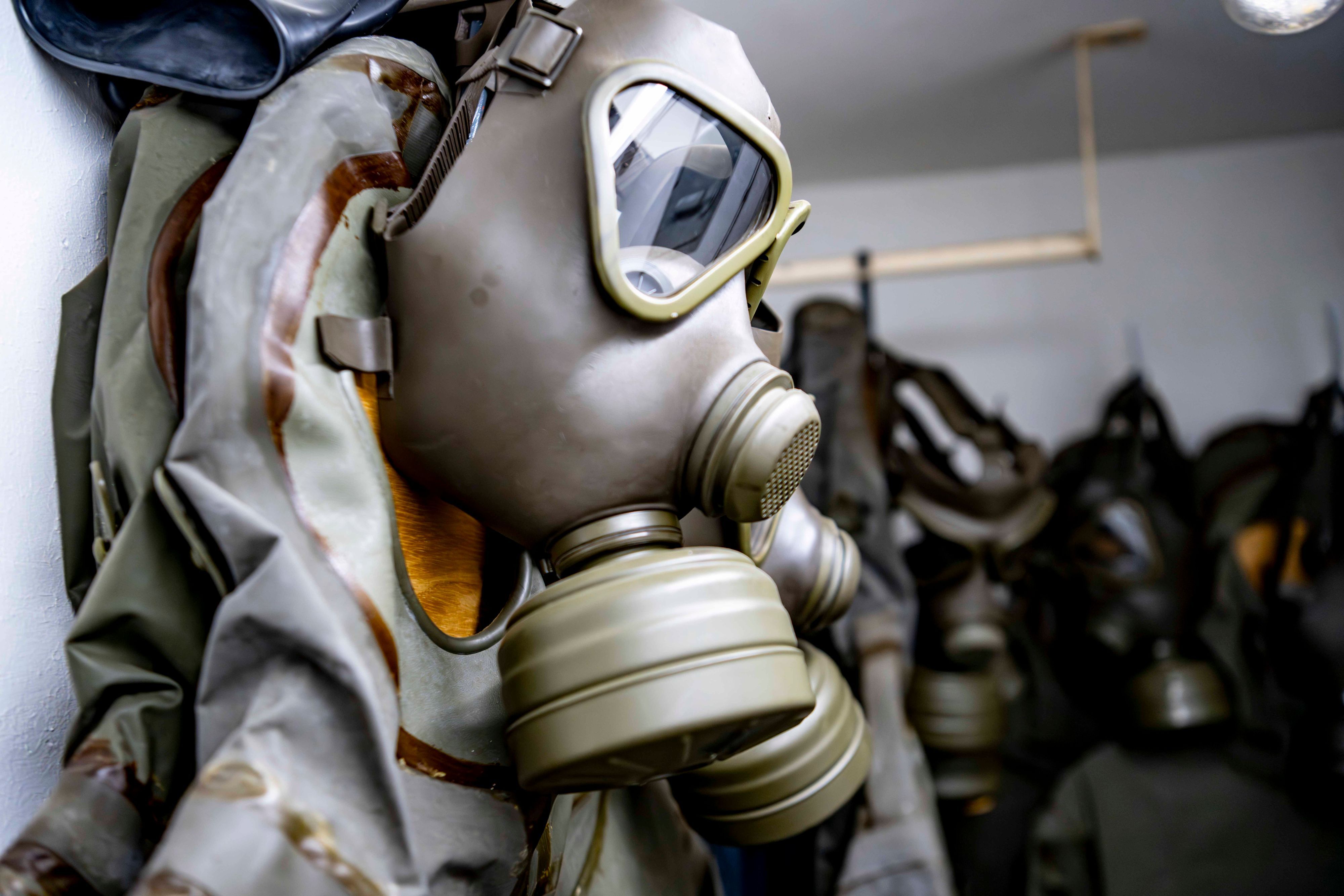 Eine Gesichtsmaske mit aufgeschraubten Filtern zum Schutz vor gefährlichen Gasen hängt an einer Wand.
