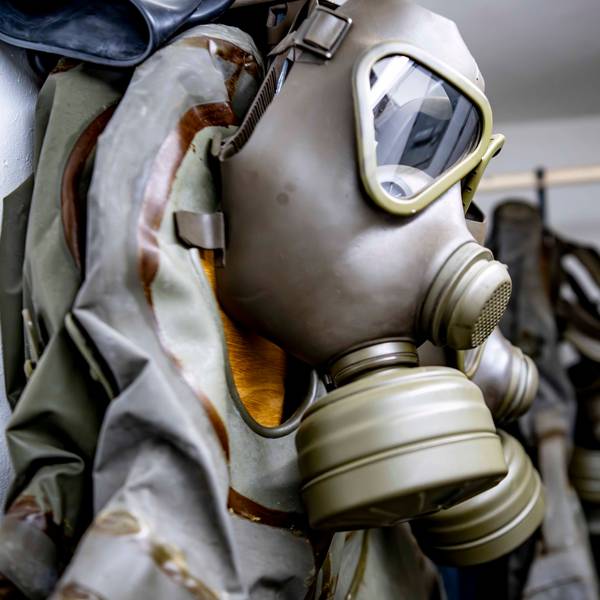 Eine Gesichtsmaske mit aufgeschraubten Filtern zum Schutz vor gefährlichen Gasen hängt an einer Wand.