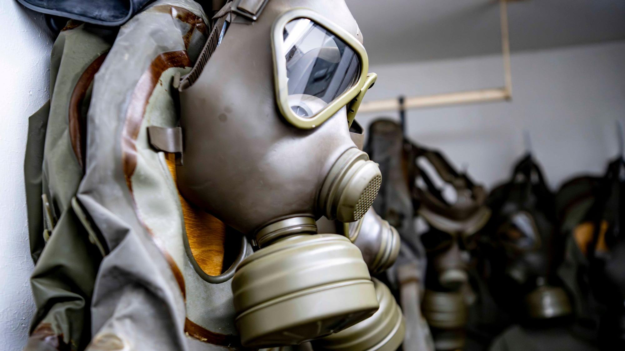 Eine Gesichtsmaske mit aufgeschraubten Filtern zum Schutz vor gefährlichen Gasen hängt an einer Wand.