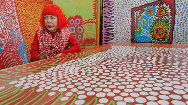 Die japanische Künstlerin Yayoi Kusama spricht während eines Interviews in ihrem Atelier, das mit wandgroßen Gemälden gefüllt ist.