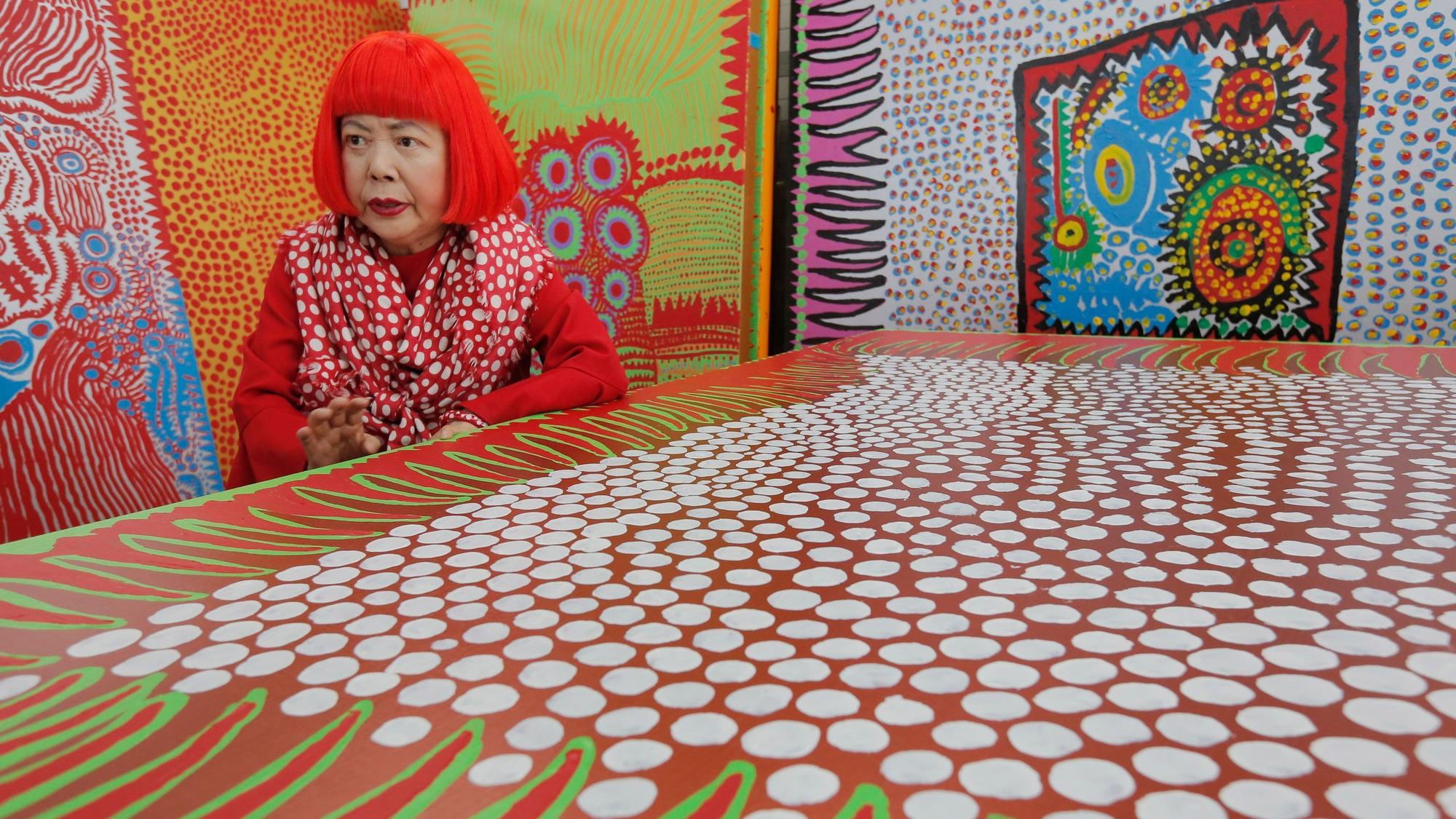 Die japanische Künstlerin Yayoi Kusama spricht während eines Interviews in ihrem Atelier, das mit wandgroßen Gemälden gefüllt ist.