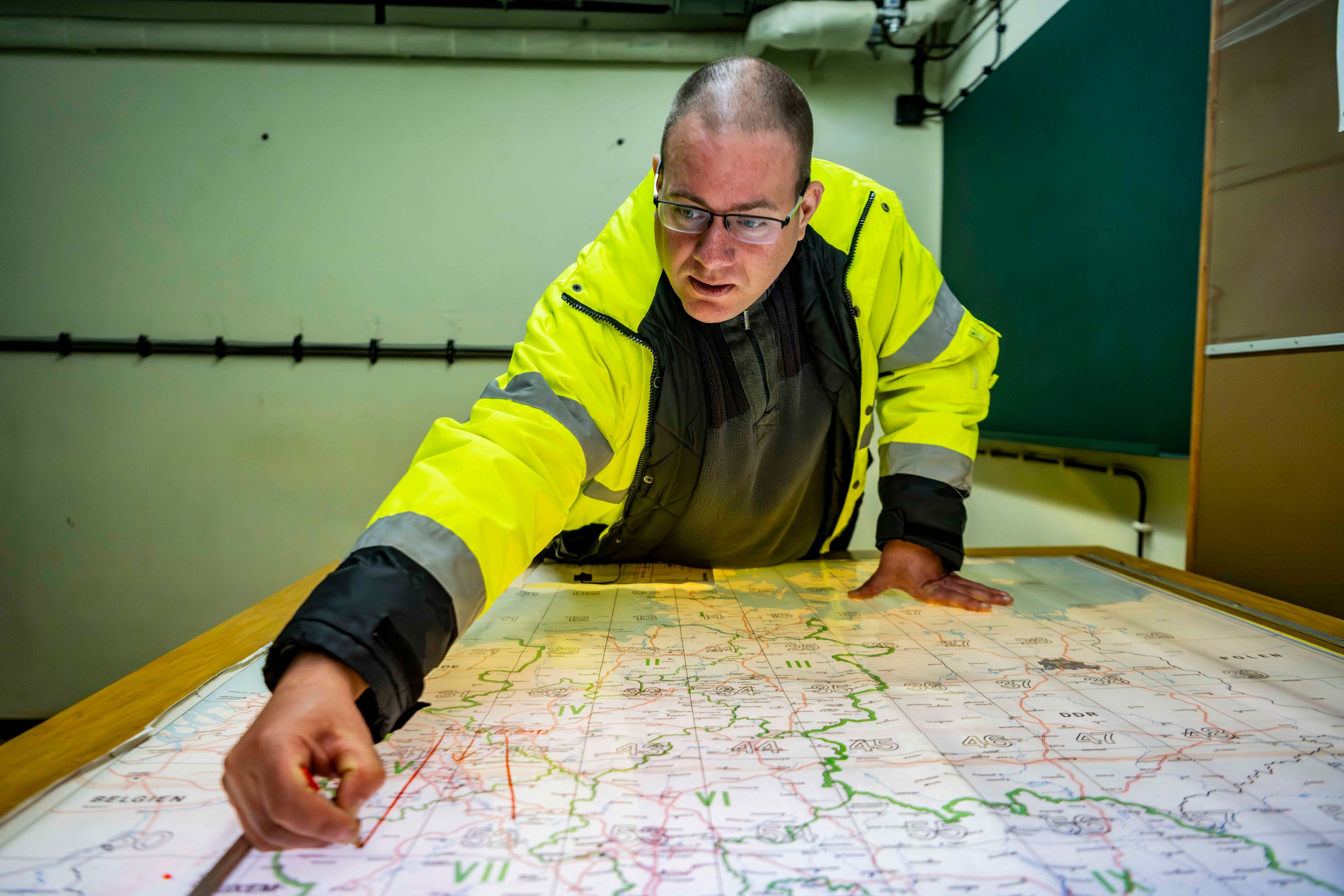 Bunker-Experte Harald Röhling beugt sich über einer Karte. Er trägt eine neon-gelbe Signaljacke.