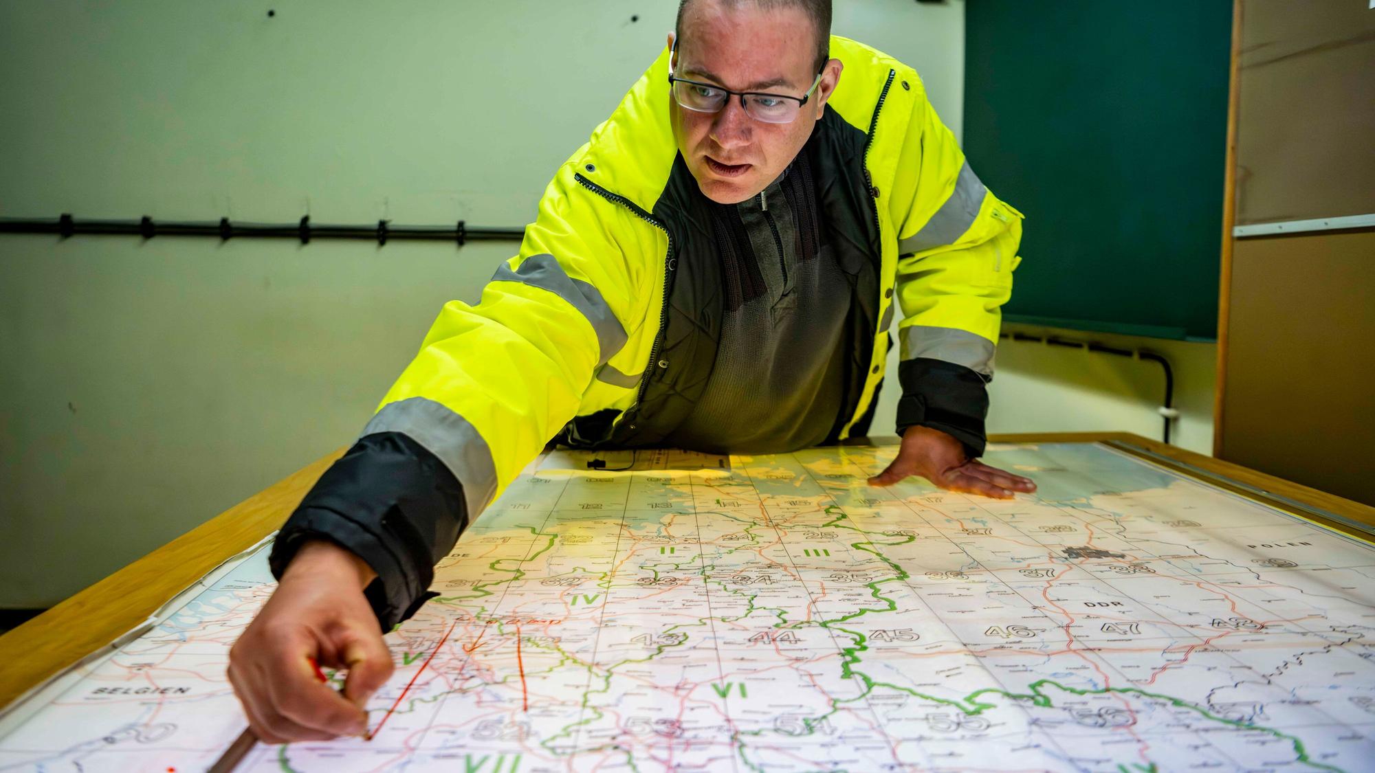Bunker-Experte Harald Röhling beugt sich über einer Karte. Er trägt eine neon-gelbe Signaljacke.