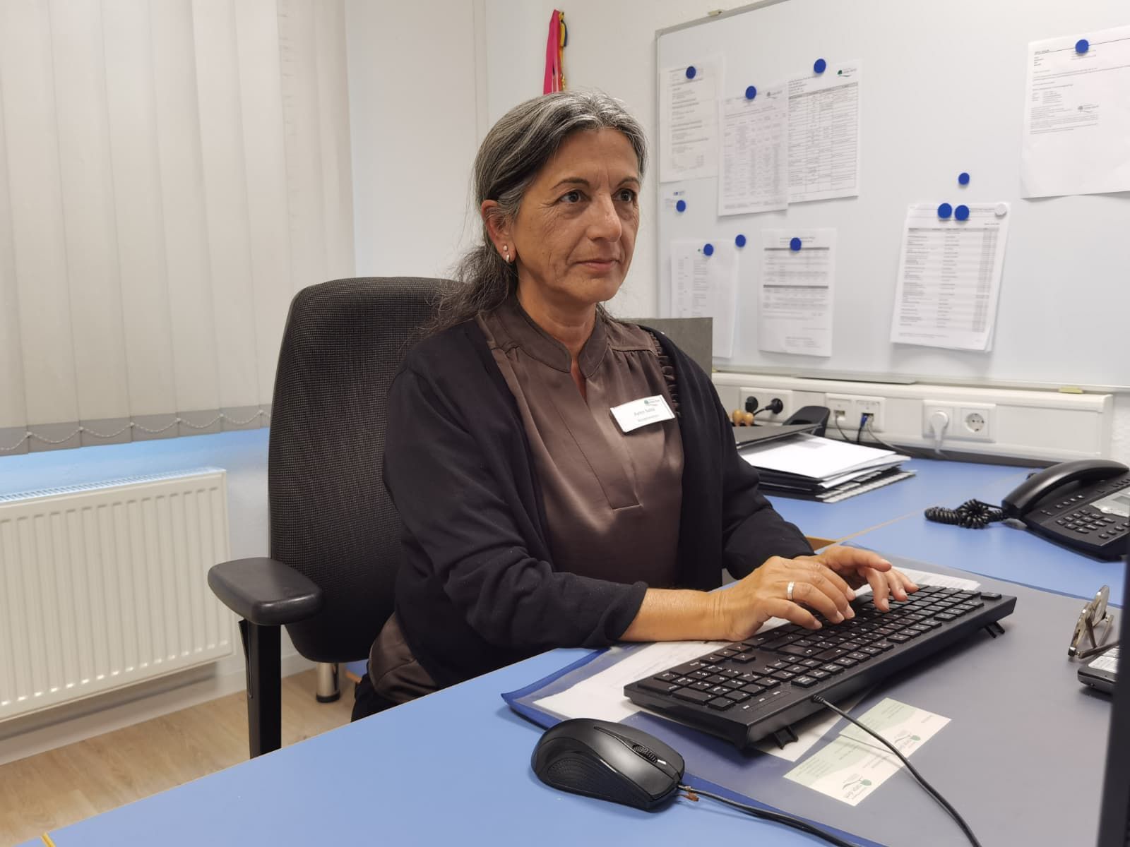 Eine Frau sitzt an einem Schreibtisch und tippt etwas in eine Tastatur.