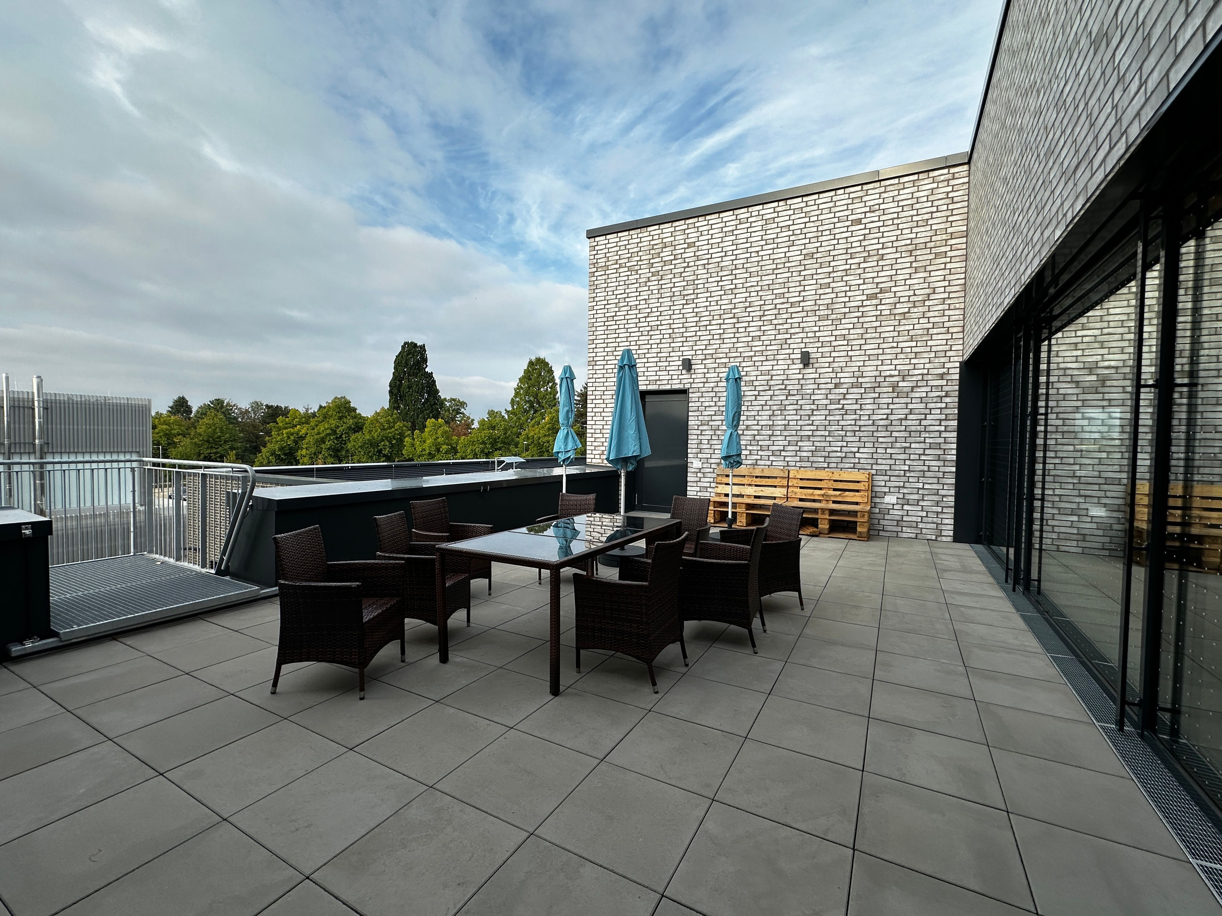Auf einer Terrasse steht ein Tisch mit Stühlen und Sonnenschirmen.