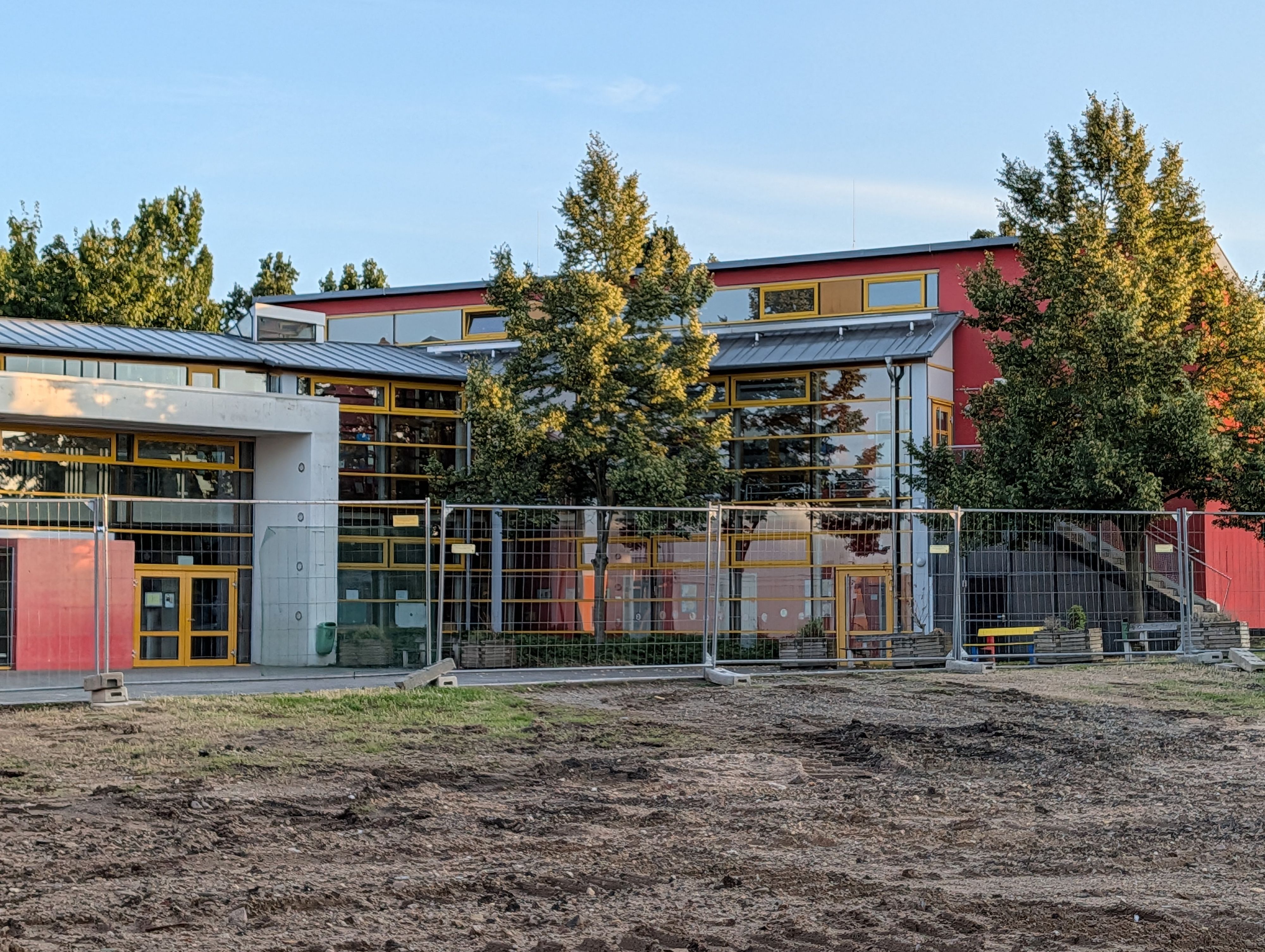 Das Foto zeigt das abgeräumte Baufeld, im Hintergrund das Schulgebäude.