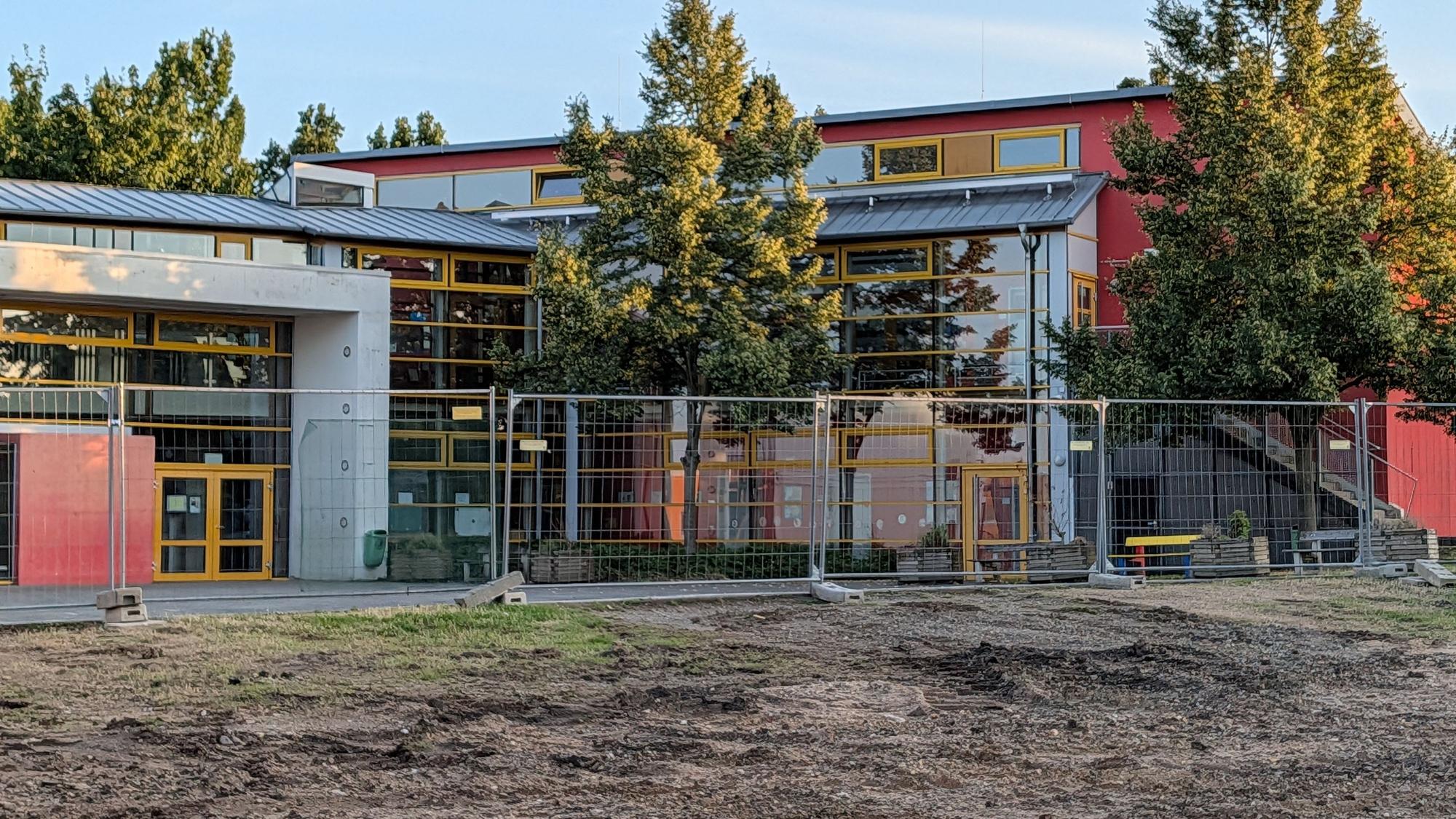 Das Foto zeigt das abgeräumte Baufeld, im Hintergrund das Schulgebäude.