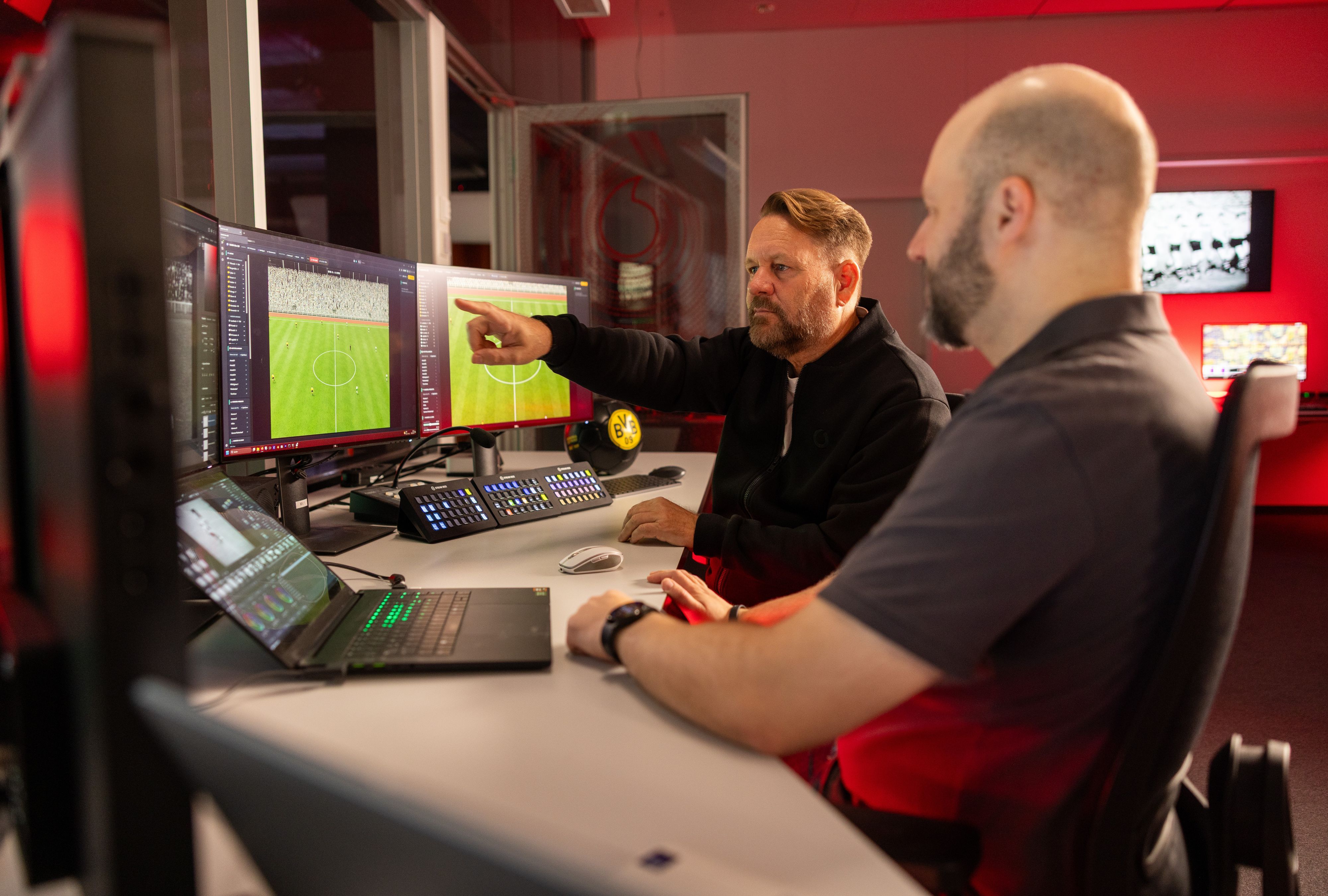 Zwei Männer sitzen vor Computerbildschirmen.