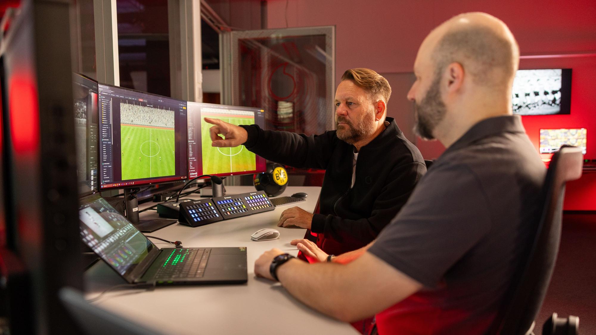 Zwei Männer sitzen vor Computerbildschirmen.