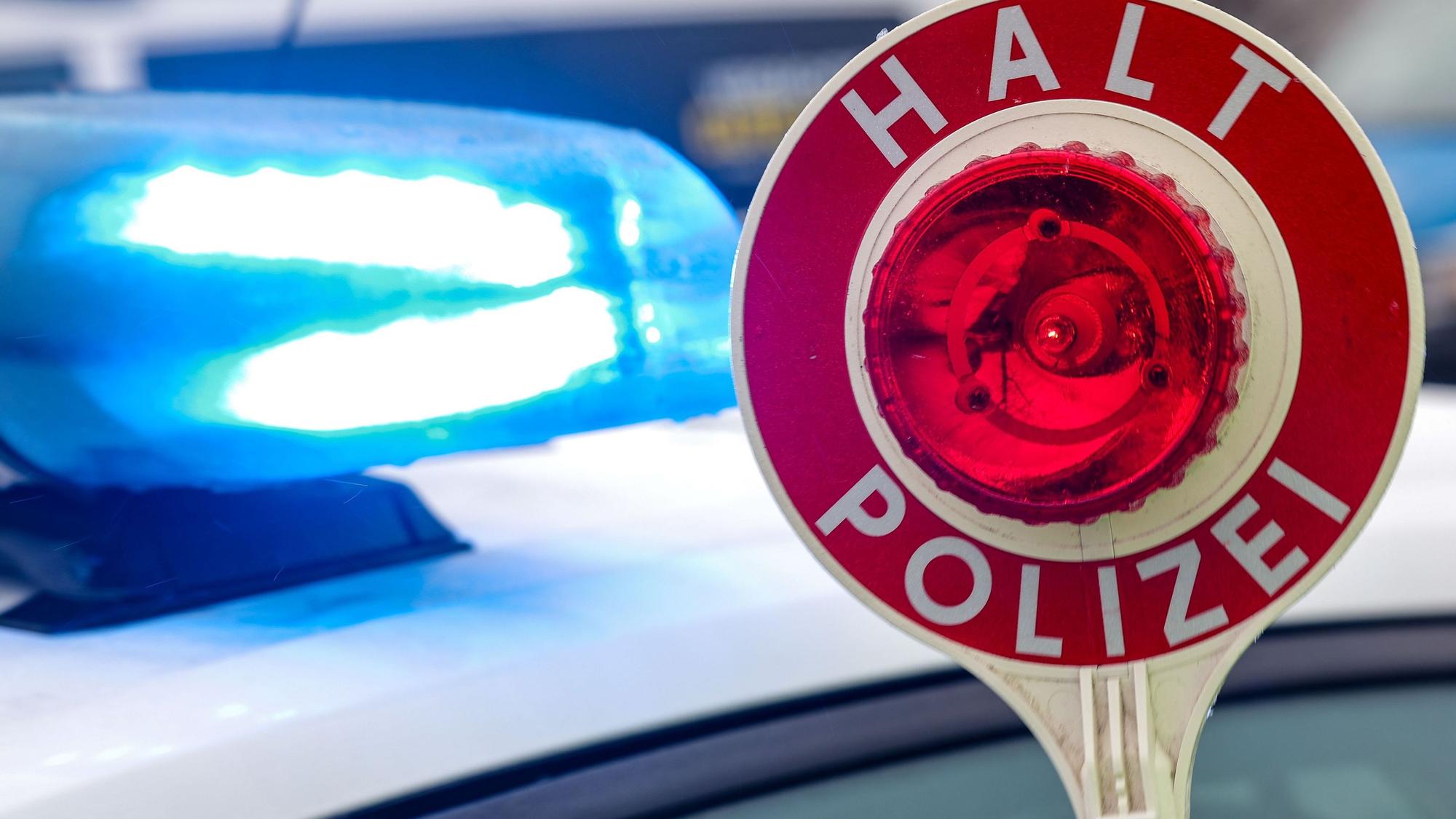 Ein Polizist hält eine Polizeikelle für eine Kontrolle.