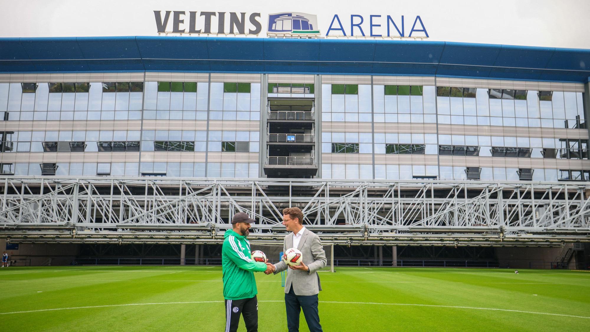 Miron Muslic, Trainer FC Schalke 04, und Hendrik Wüst (CDU), Ministerpräsident des Landes Nordrhein-Westfalen, stehen zusammen auf dem Rasen vor der Veltins-Arena.