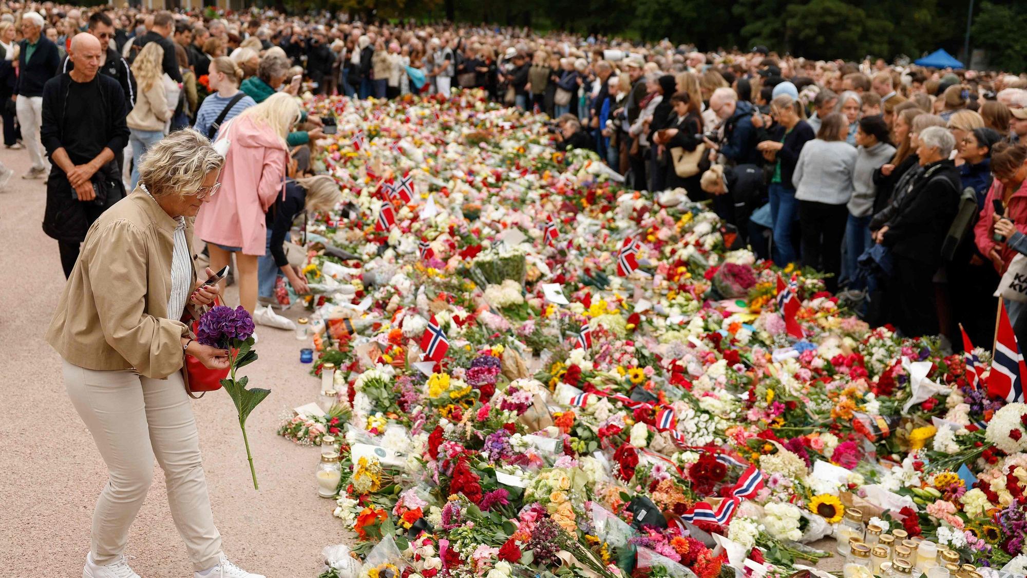 Der Platz vor dem Schloss verwandelt sich zunehmend in ein Blumenmeer, während Zehntausende Menschen kommen, um dem verstorbenen König die letzte Ehre zu erweisen.