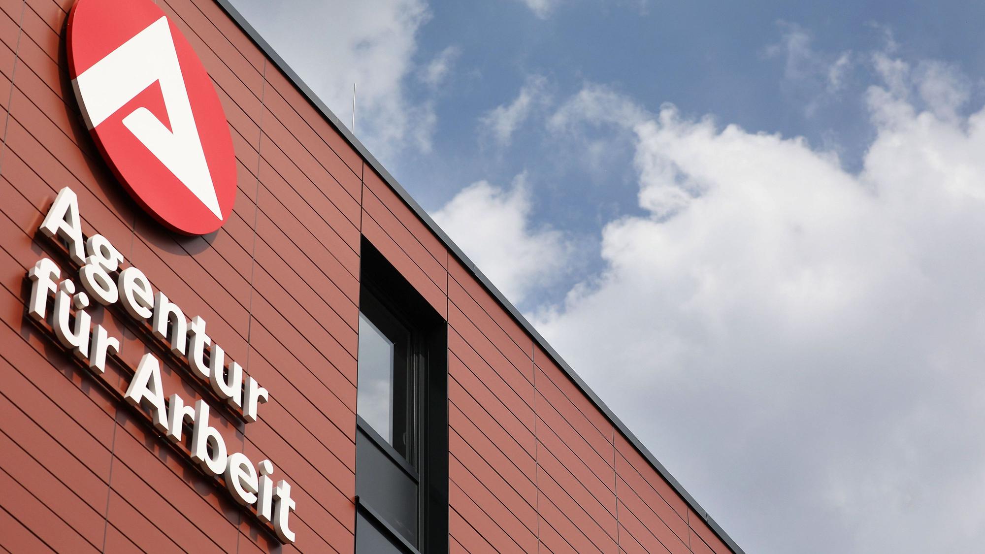 Ein Logo hängt am Gebäude der Agentur für Arbeit.