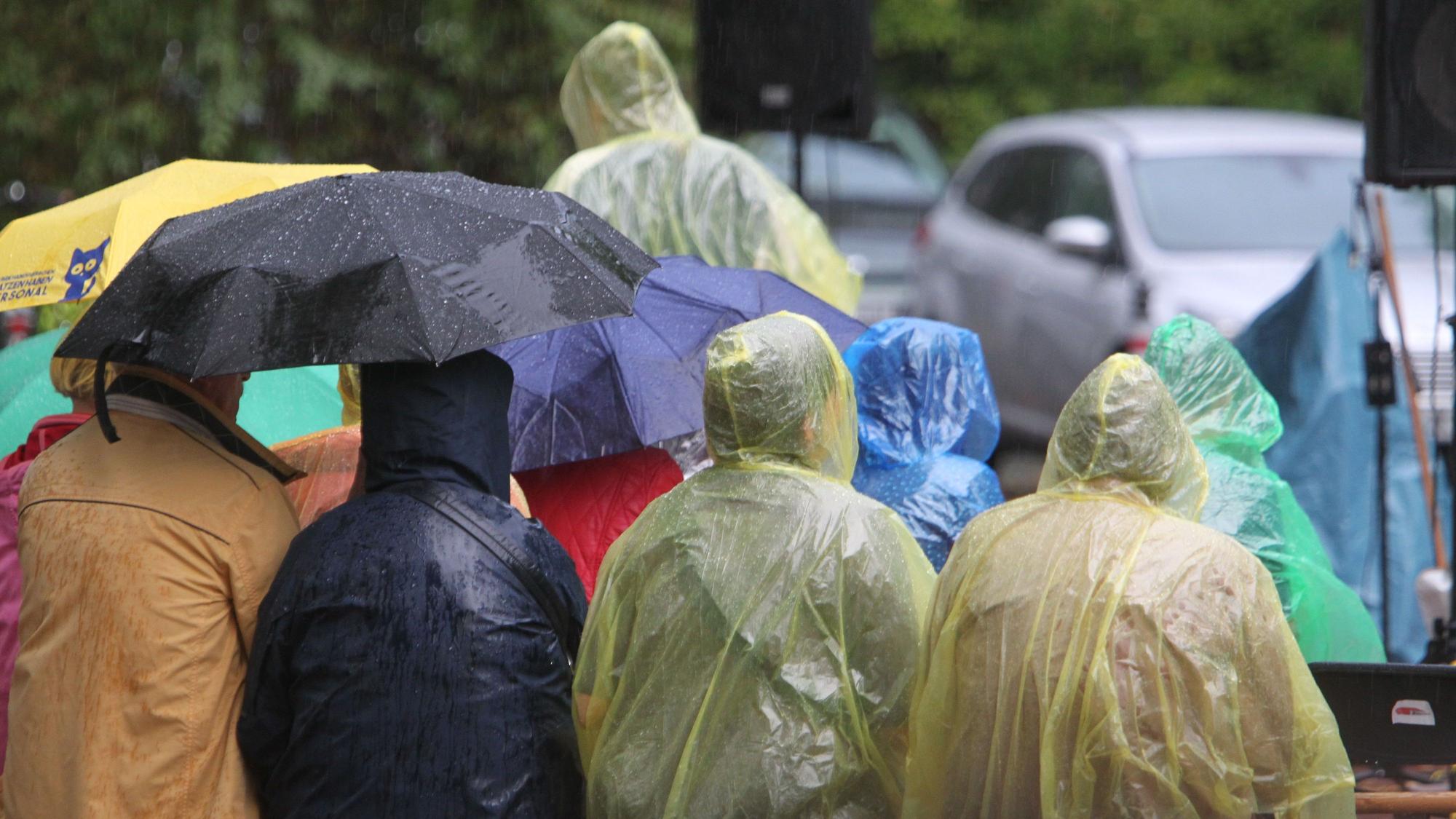Unter gelben Regencapes der Stadtwerke schützen sich die Besucher vor dem schlechten Wetter.