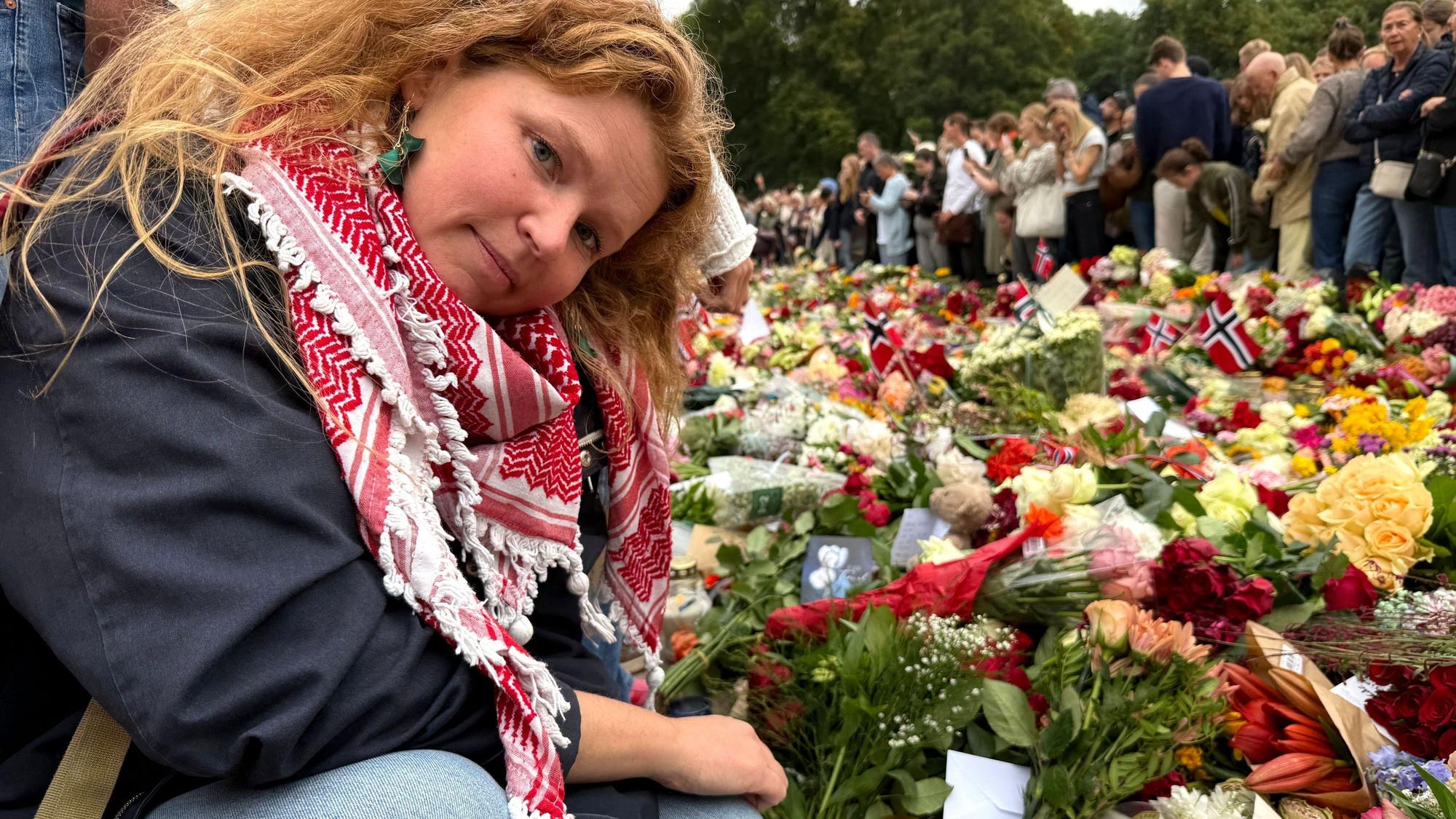 Die Lehrerin Ida Berg Knudsen legt Briefe, die ihre Schülerinnen und Schüler für den verstorbenen König Harald geschrieben haben, zwischen den vor dem Königlichen Schloss Oslo abgelegten Blumen ab.
