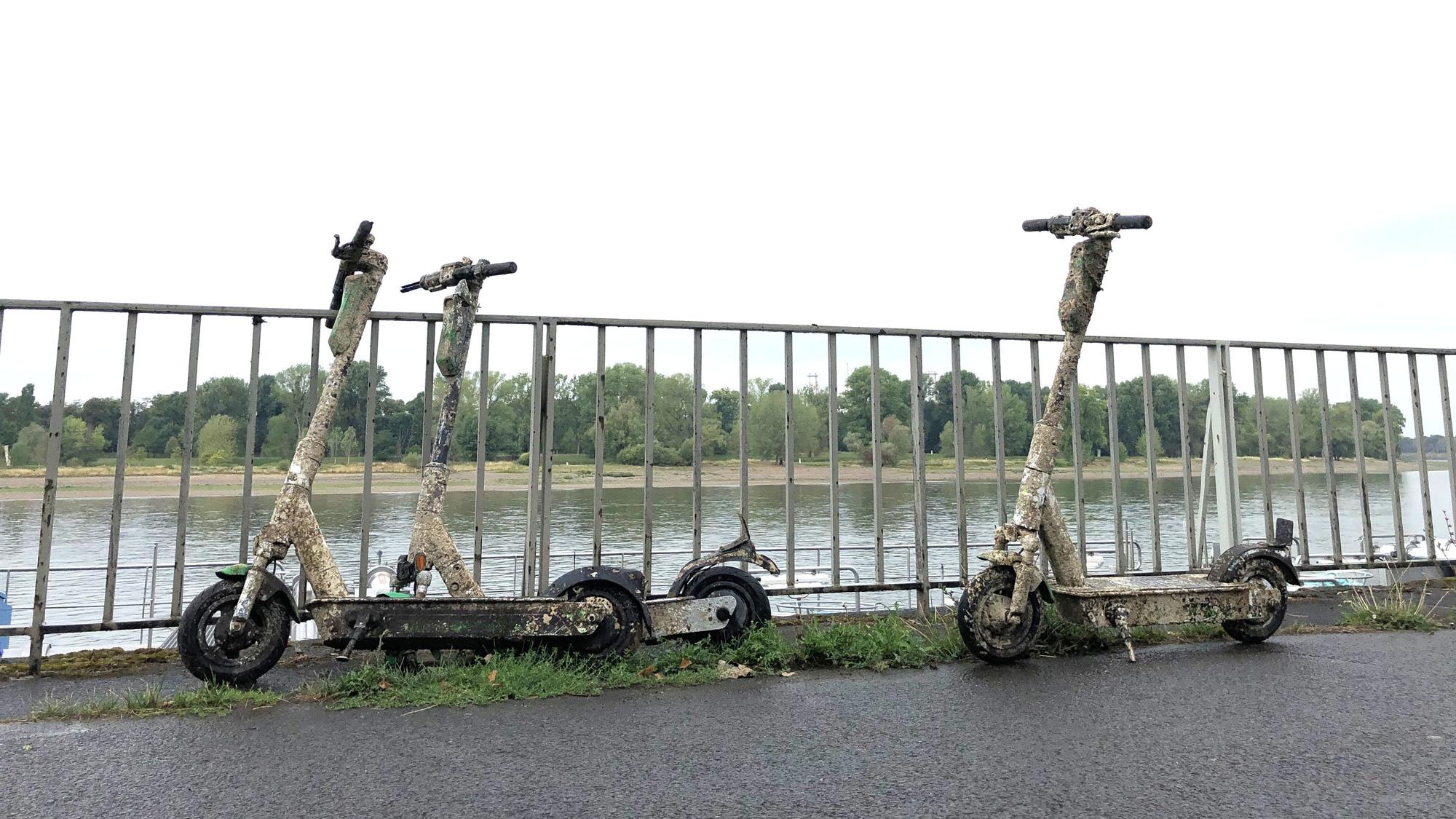 E-Scooter, die aus dem Rhein geholt wurden, stehen am Rheinufer in Köln-Mülheim