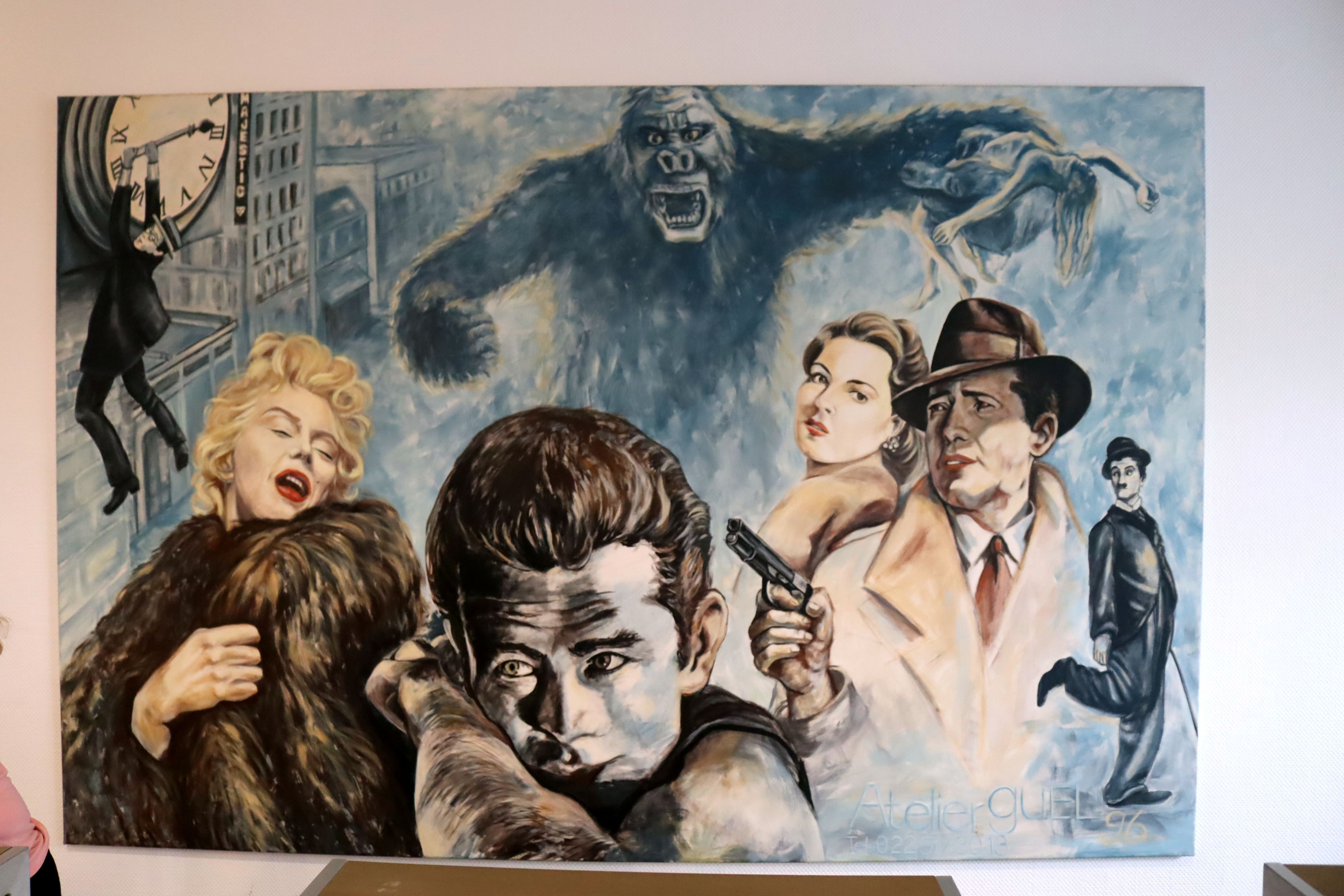 Auf einer Leinwand sind Buster Keaton, Marilyn Monroe, James Dean, Ingrid Bergman, Humphrey Bogart, Charles Chaplin und King Kong zu sehen.