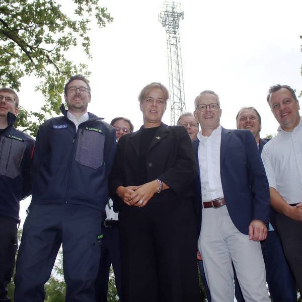 Eine Gruppe Menschen steht vor einem Mobilfunkmast an der Steinbachtalsperre bei Euskirchen.