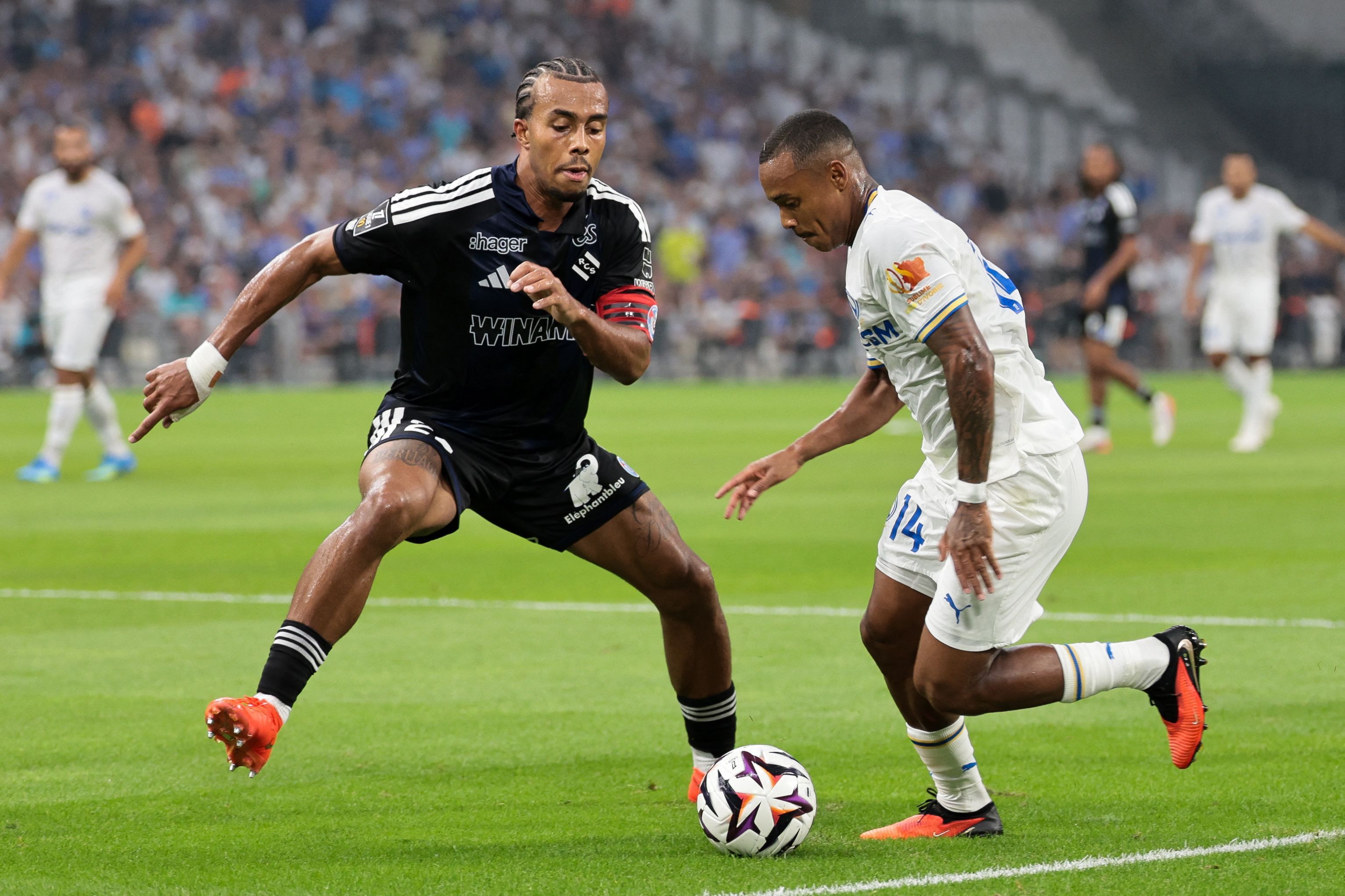 Strasbourg's Ivorian defender #22 Guela Doue (L) fights for the ball with Marseille's Brazilian forward #14 Igor Paixao during the French L1 football match between Olympique de Marseille (OM) and RC Strasbourg Alsace at the Stade Velodrome in Marseille, south-eastern France on August 21, 2026. (Photo by Pascal POCHARD-CASABIANCA / AFP)