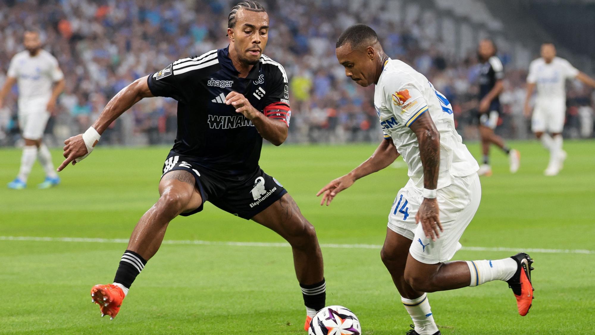 Strasbourg's Ivorian defender #22 Guela Doue (L) fights for the ball with Marseille's Brazilian forward #14 Igor Paixao during the French L1 football match between Olympique de Marseille (OM) and RC Strasbourg Alsace at the Stade Velodrome in Marseille, south-eastern France on August 21, 2026. (Photo by Pascal POCHARD-CASABIANCA / AFP)
