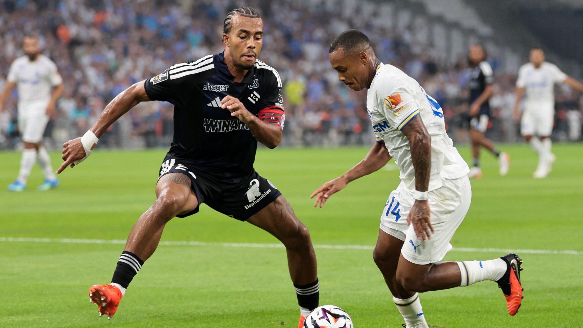 Strasbourg's Ivorian defender #22 Guela Doue (L) fights for the ball with Marseille's Brazilian forward #14 Igor Paixao during the French L1 football match between Olympique de Marseille (OM) and RC Strasbourg Alsace at the Stade Velodrome in Marseille, south-eastern France on August 21, 2026. (Photo by Pascal POCHARD-CASABIANCA / AFP)
