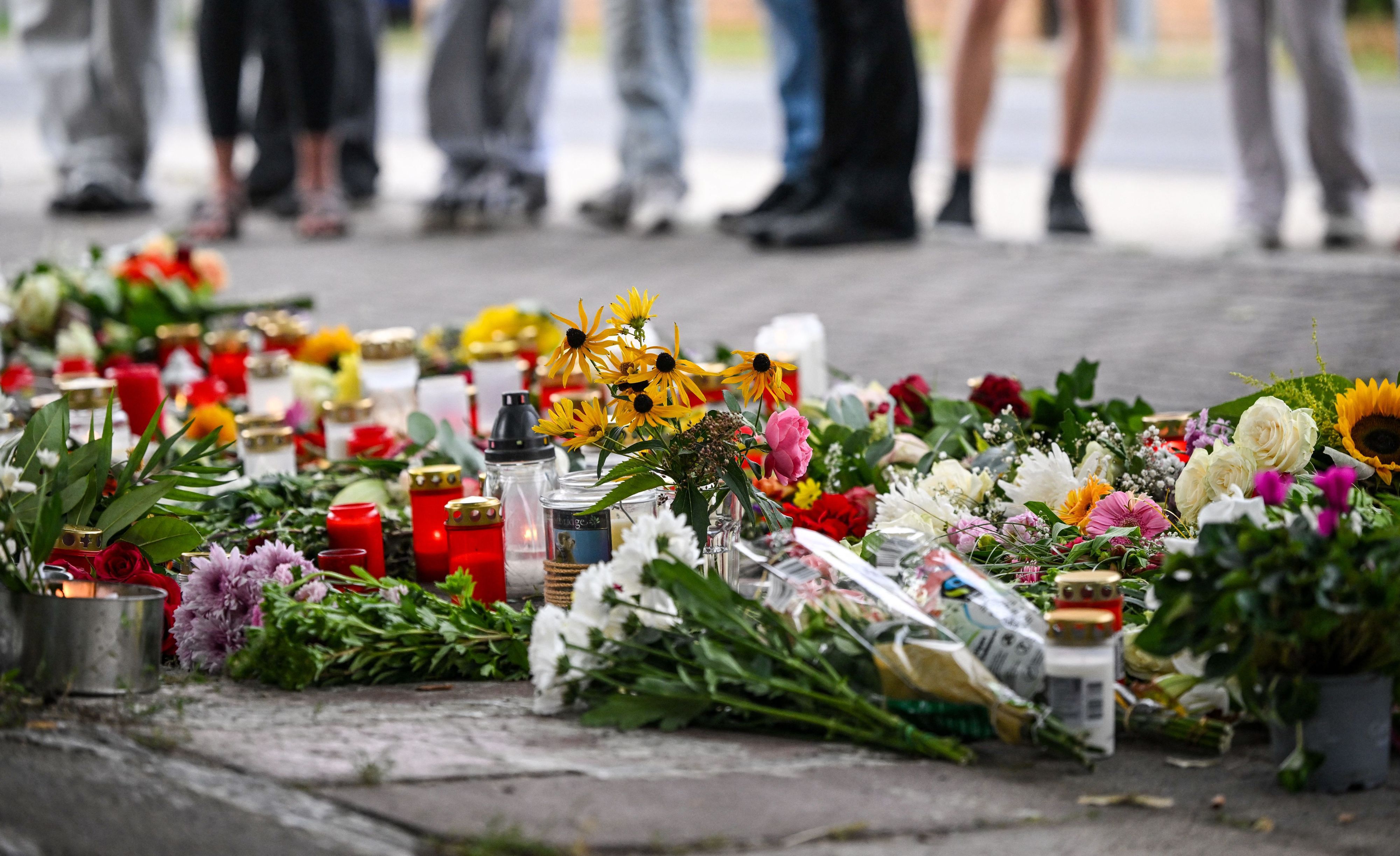 Blumen und Kerzen liegen vor einer Schule im Landkreis Oder-Spree. Dort wurden eine 18-jährige Schülerin und ein 30-jähriger Kita-Erzieher getötet.