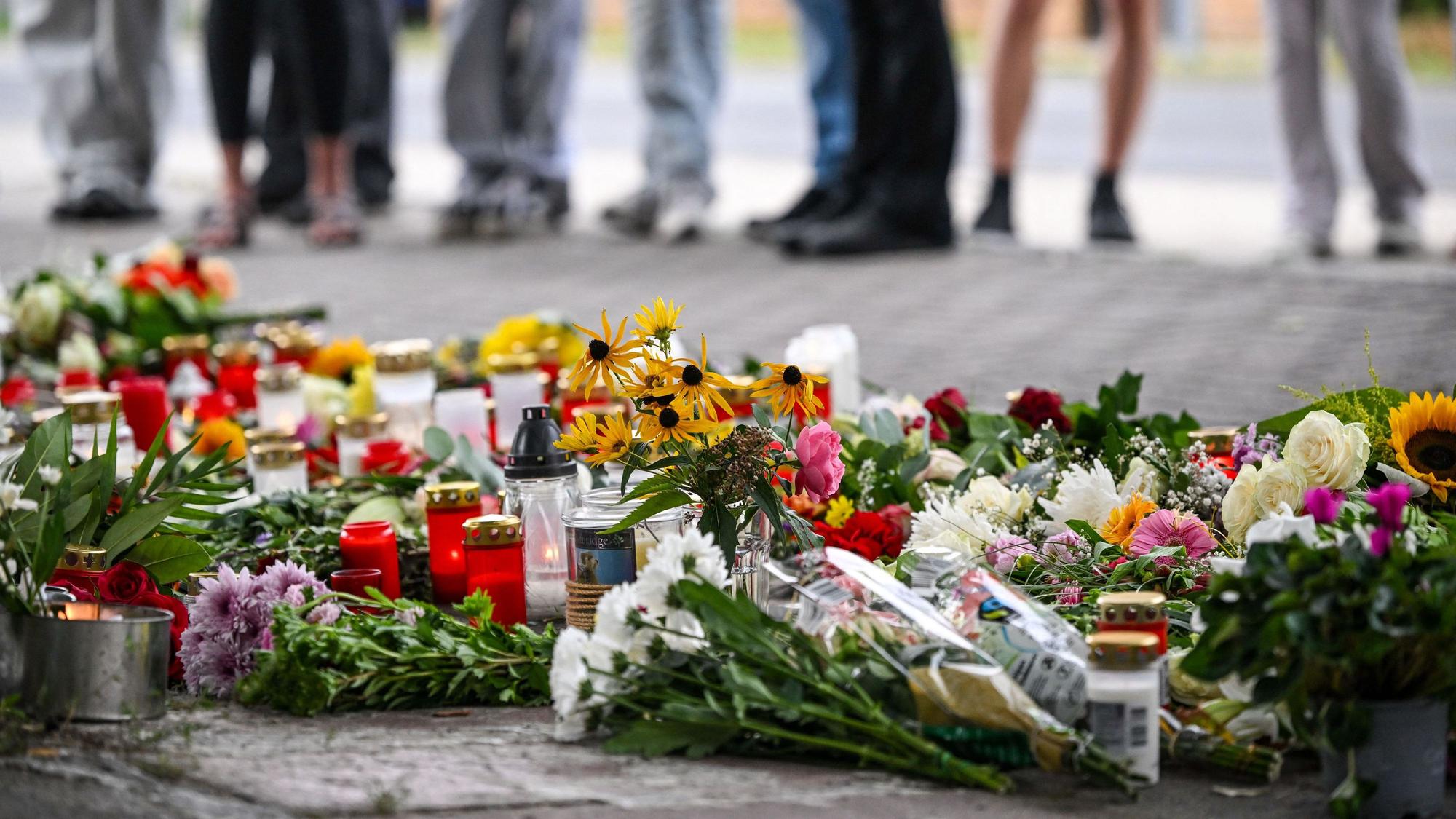 Blumen und Kerzen liegen vor einer Schule im Landkreis Oder-Spree. Dort wurden eine 18-jährige Schülerin und ein 30-jähriger Kita-Erzieher getötet.