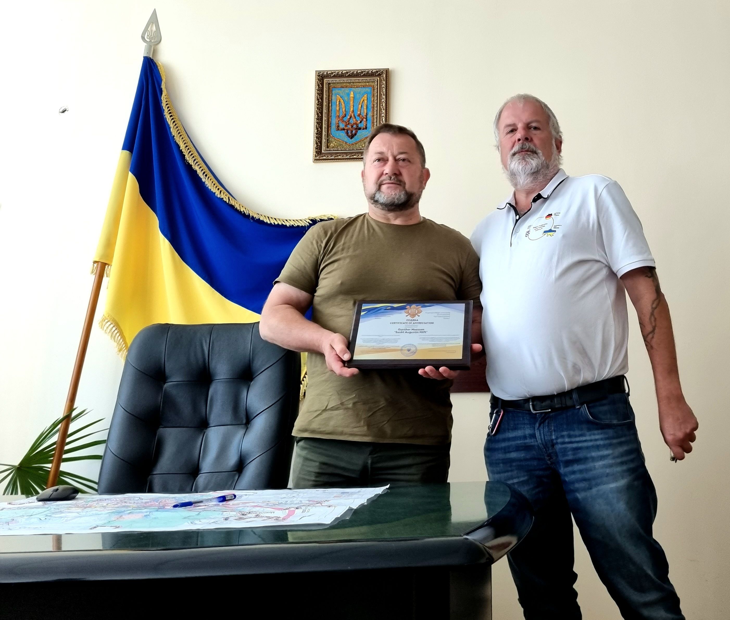 Zwei Männer neben einer ukrainischen Flagge.