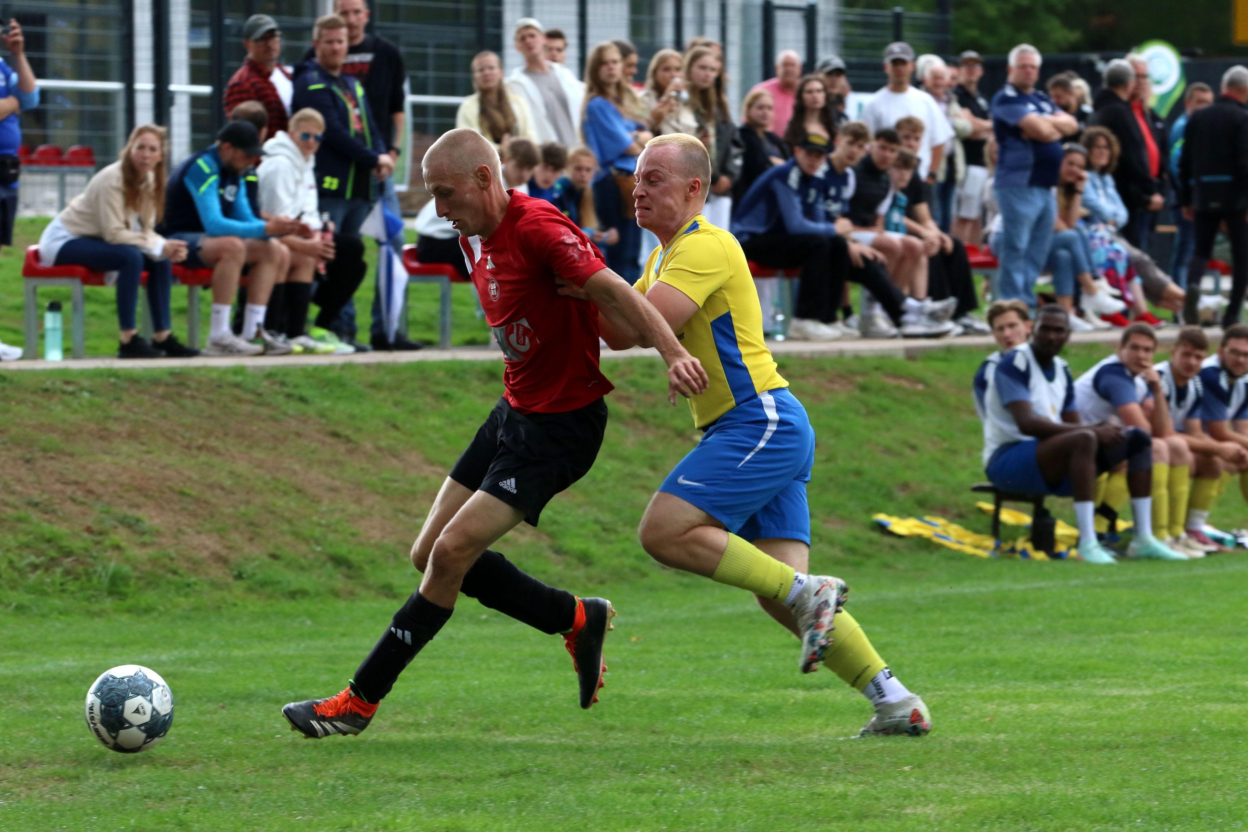 Ein Kommerner Spieler schubst einen Gegenspieler. Im Hintergrund sind zahlreiche Zuschauer zu sehen.