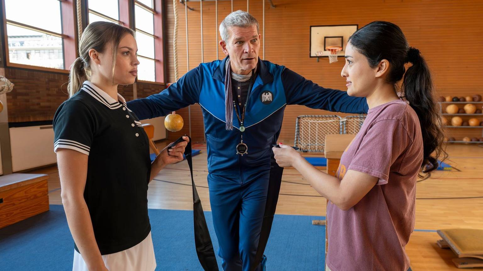 Agenten-Sitcom „Spyon“ in der ZDF-Mediathek: Die Studis Victoria (Lea Zoë Voss, links ) und Sami (Sogol Faghani) müssen den sportlichen Eignungstest bei Ausbilder Voss (Götz Otto) bestehen. (Bild: ZDF und susanne bernhard)