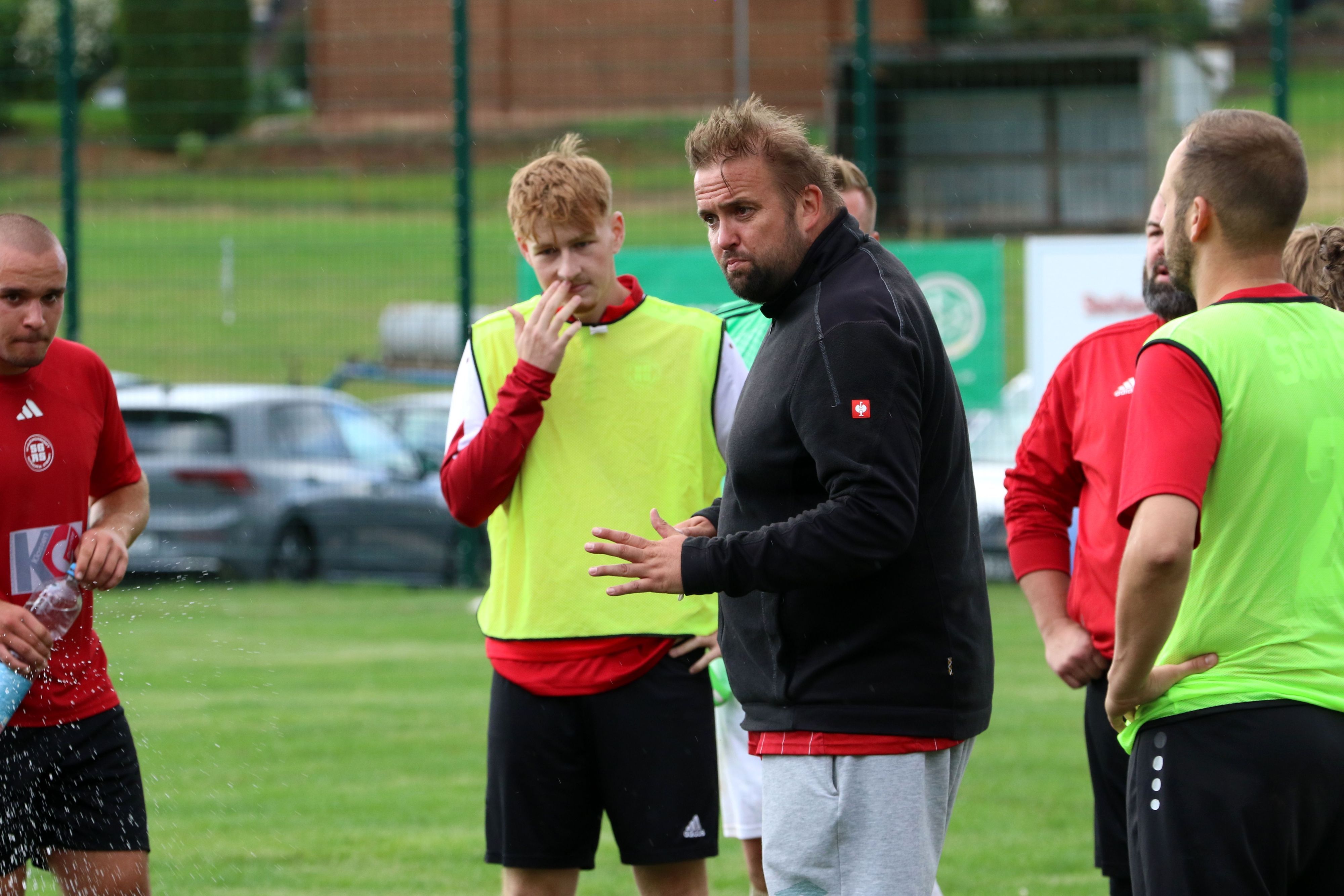 Der Trainer von Rotbachtal/Strempt gib inmitten seiner Spieler Anweisungen.