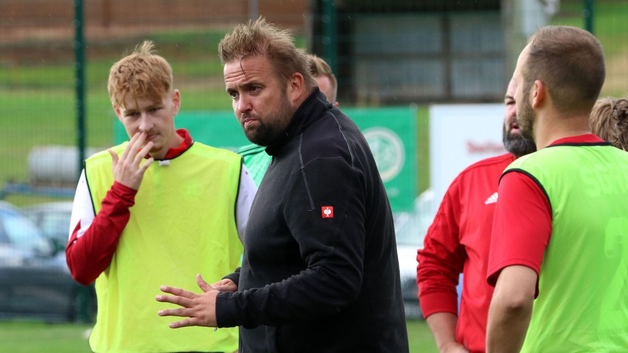 Der Trainer von Rotbachtal/Strempt gib inmitten seiner Spieler Anweisungen.