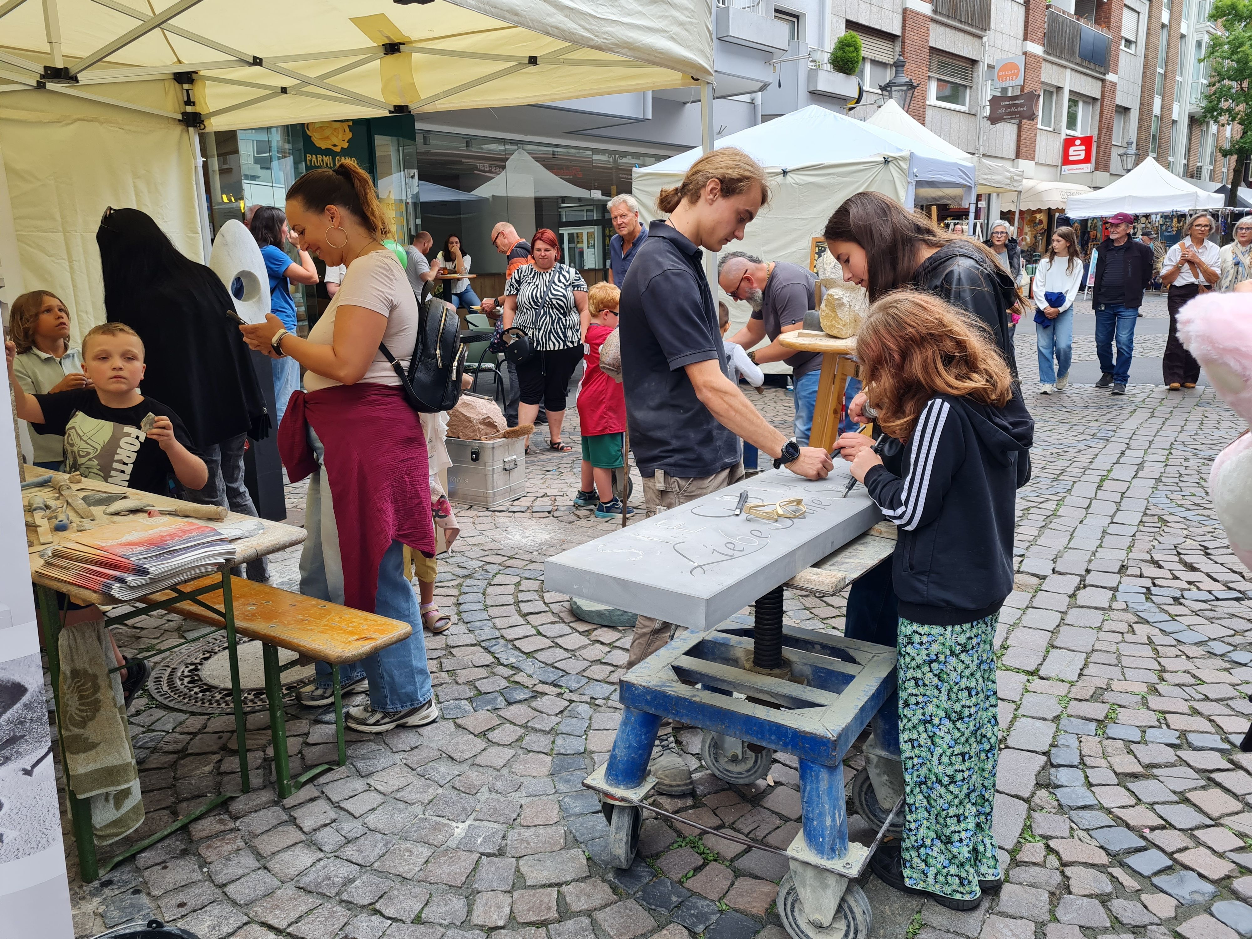 Kinder und Erwachsene beim Bildhauern auf einem Straßenfest