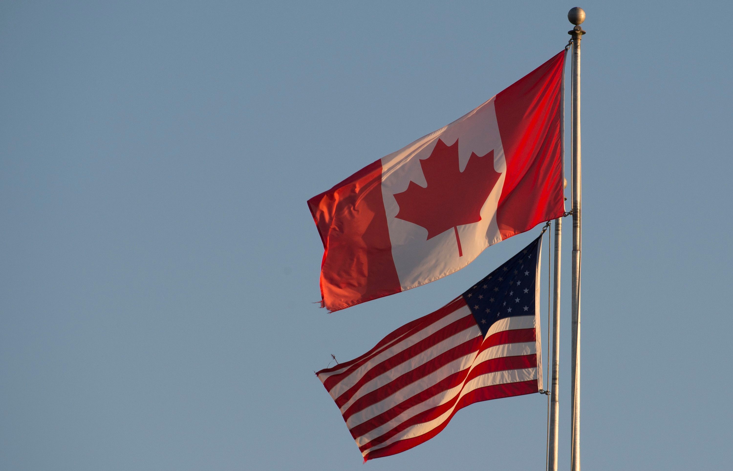ARCHIV - 20.03.2020, Kanada, Surrey: Die kanadische (oben) und die US-amerikanische Flagge sind auf dem Friedensbogen an der kanadisch-US-amerikanischen Grenze in Britisch-Kolumbien zu sehen.