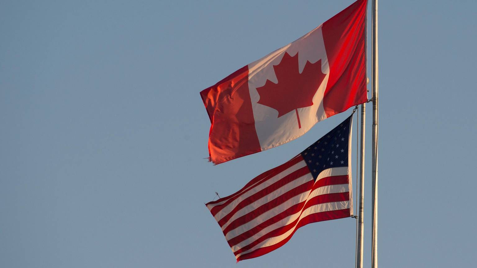 ARCHIV - 20.03.2020, Kanada, Surrey: Die kanadische (oben) und die US-amerikanische Flagge sind auf dem Friedensbogen an der kanadisch-US-amerikanischen Grenze in Britisch-Kolumbien zu sehen.