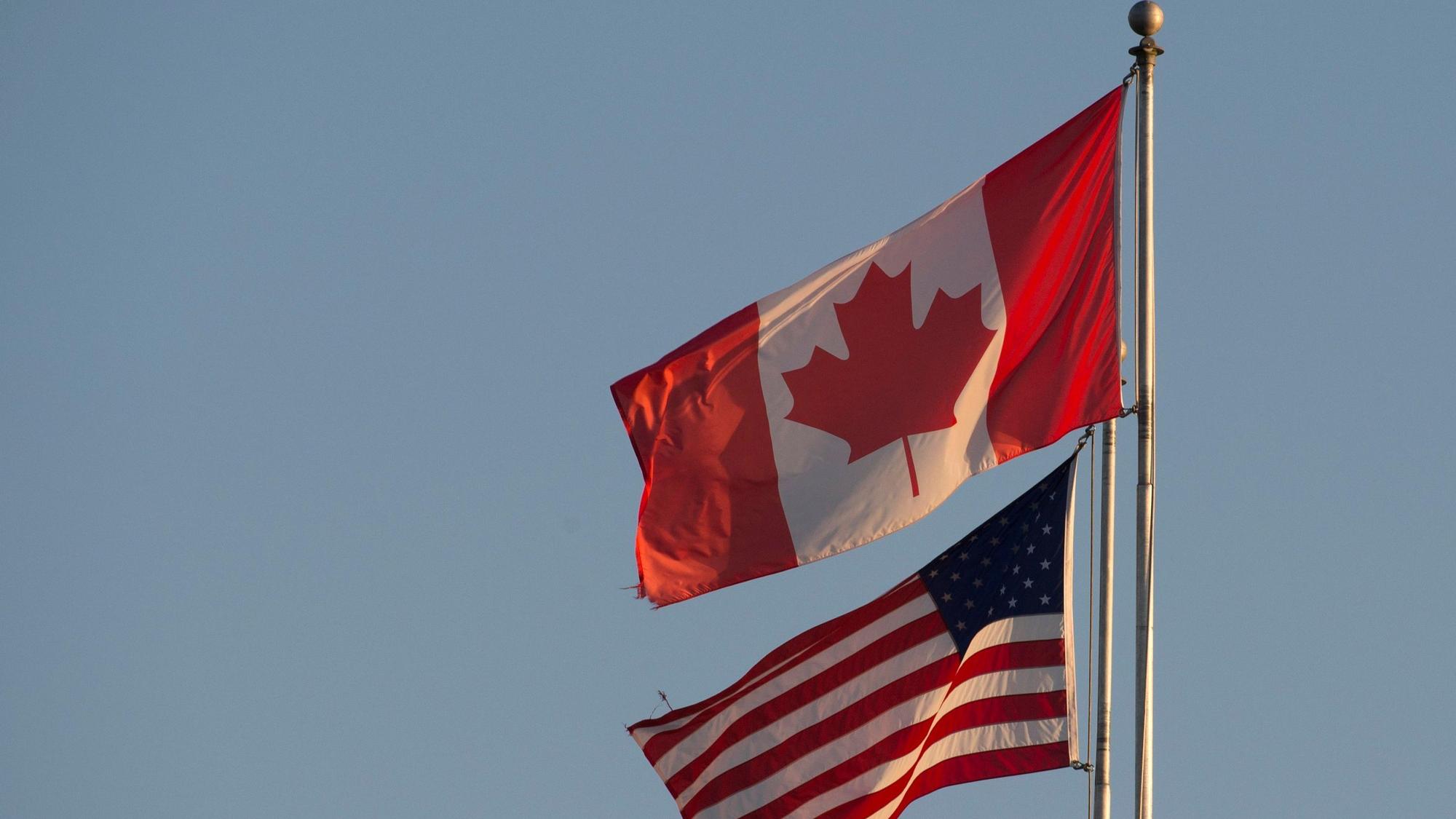 ARCHIV - 20.03.2020, Kanada, Surrey: Die kanadische (oben) und die US-amerikanische Flagge sind auf dem Friedensbogen an der kanadisch-US-amerikanischen Grenze in Britisch-Kolumbien zu sehen.