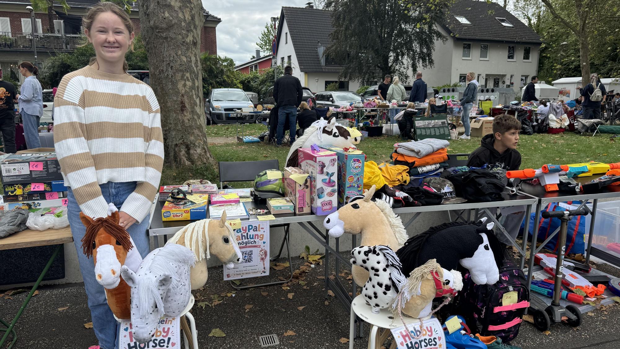 Die 13-jährige Stella aus Hitdorf verkauft beim Kindertrödel ihre selbst hergestellten Steckenpferde.