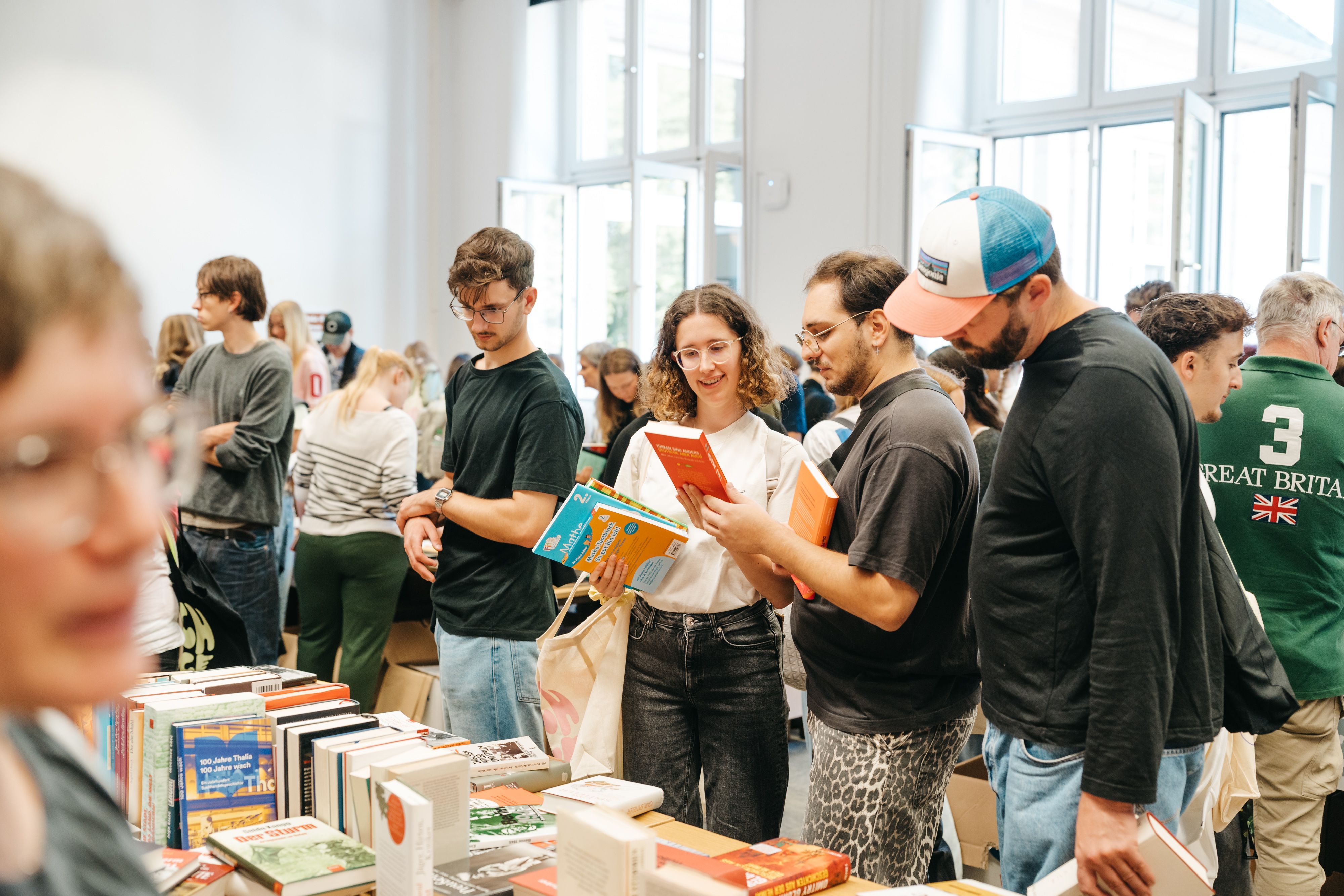 Menschen schauen sich Bücher auf der Bücherbörse an der TH Köln an.