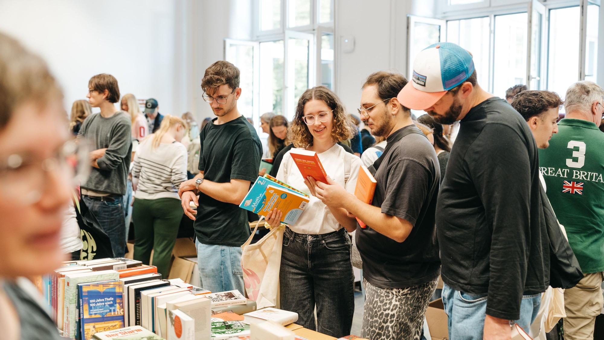Menschen schauen sich Bücher auf der Bücherbörse an der TH Köln an.