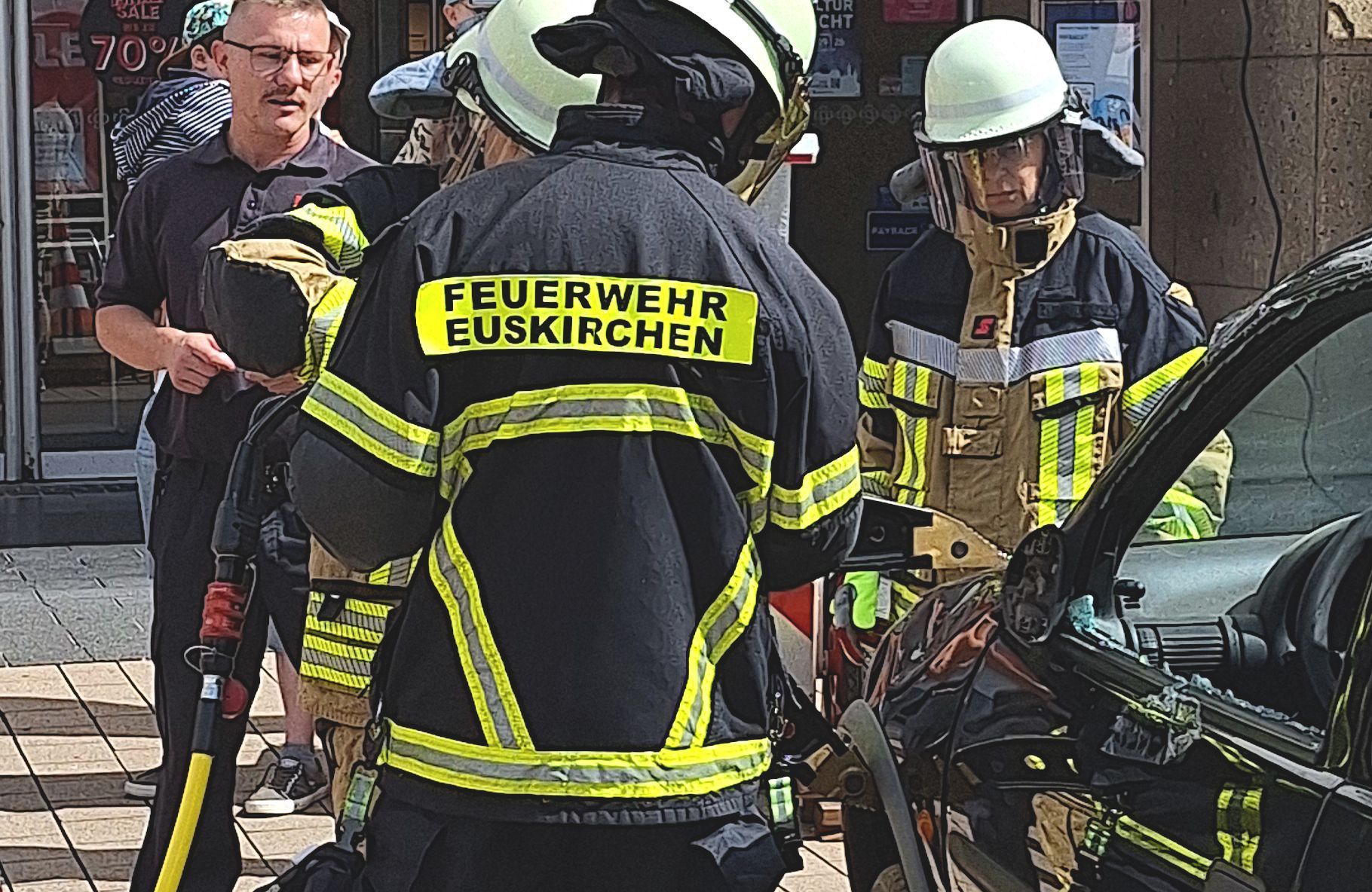 Leute in Feuerwehrausrüstung hantieren mit einem Spreizer an einem Auto.