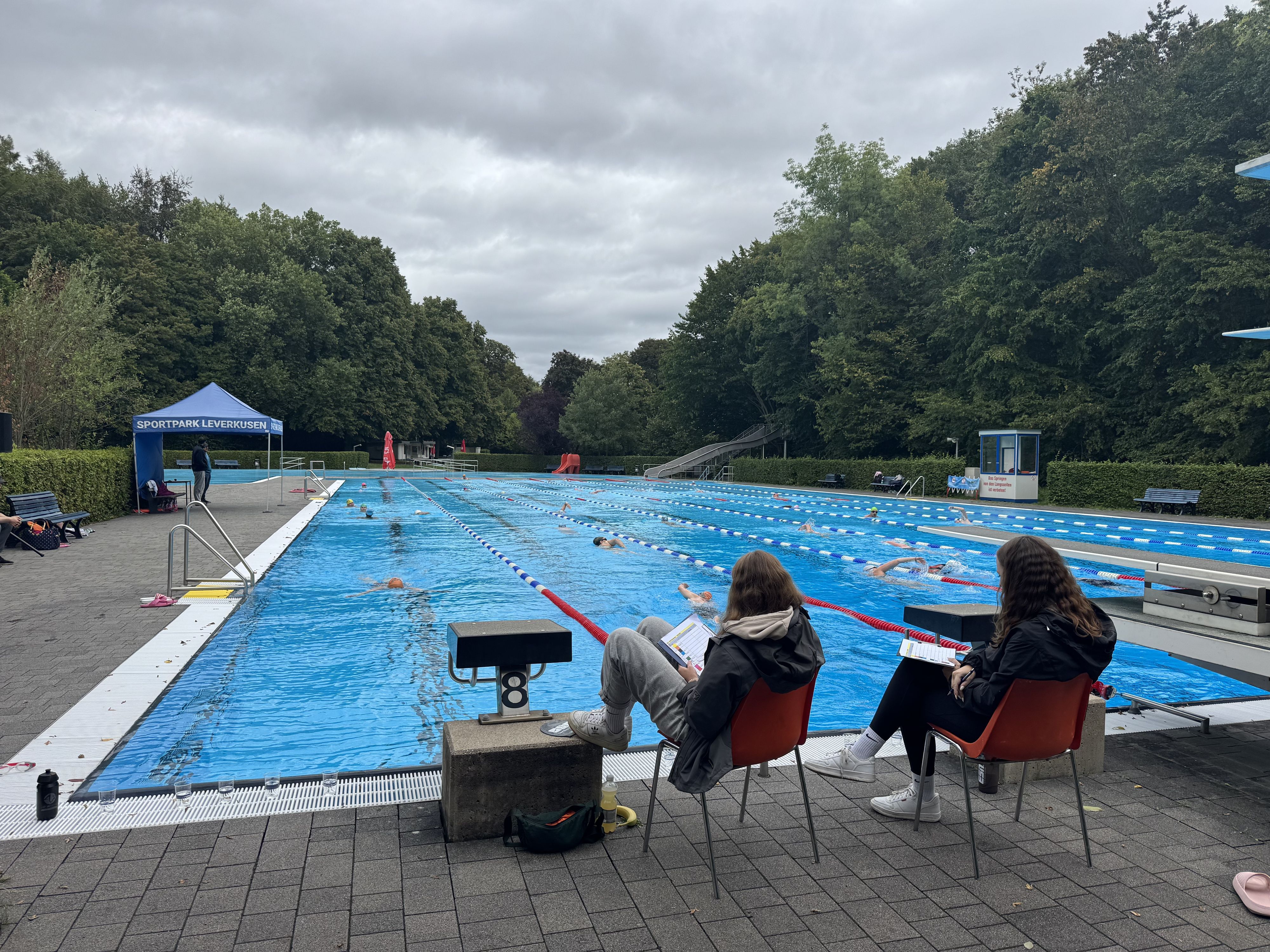 Am Ende jeder der acht Schwimmbahnen notiert sich ein Mitarbeiter des Sportpark Leverkusens die Anzahl der Bahnen, die die Teilnehmenden schon hinter sich gebracht haben.