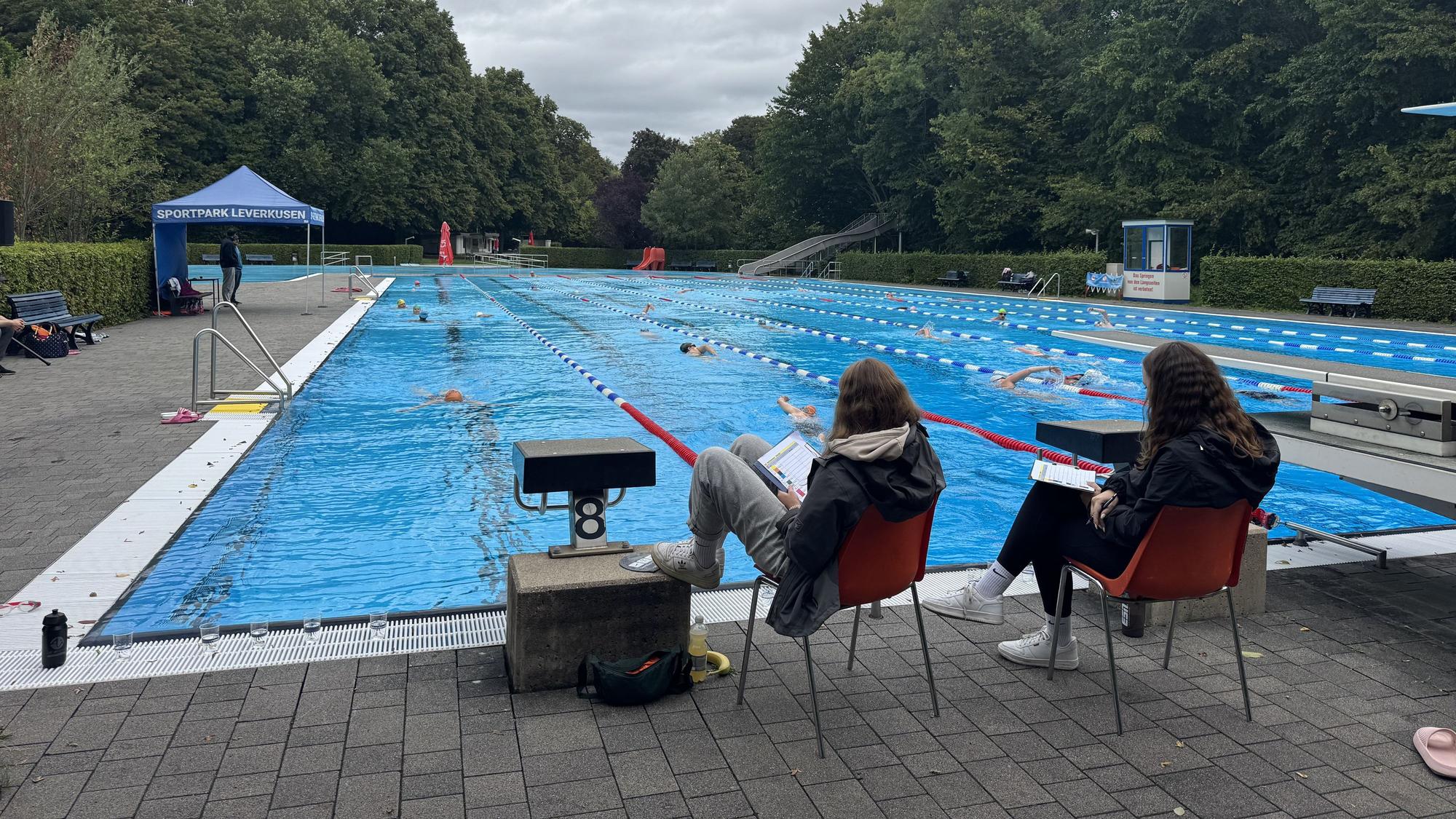 Am Ende jeder der acht Schwimmbahnen notiert sich ein Mitarbeiter des Sportpark Leverkusens die Anzahl der Bahnen, die die Teilnehmenden schon hinter sich gebracht haben.